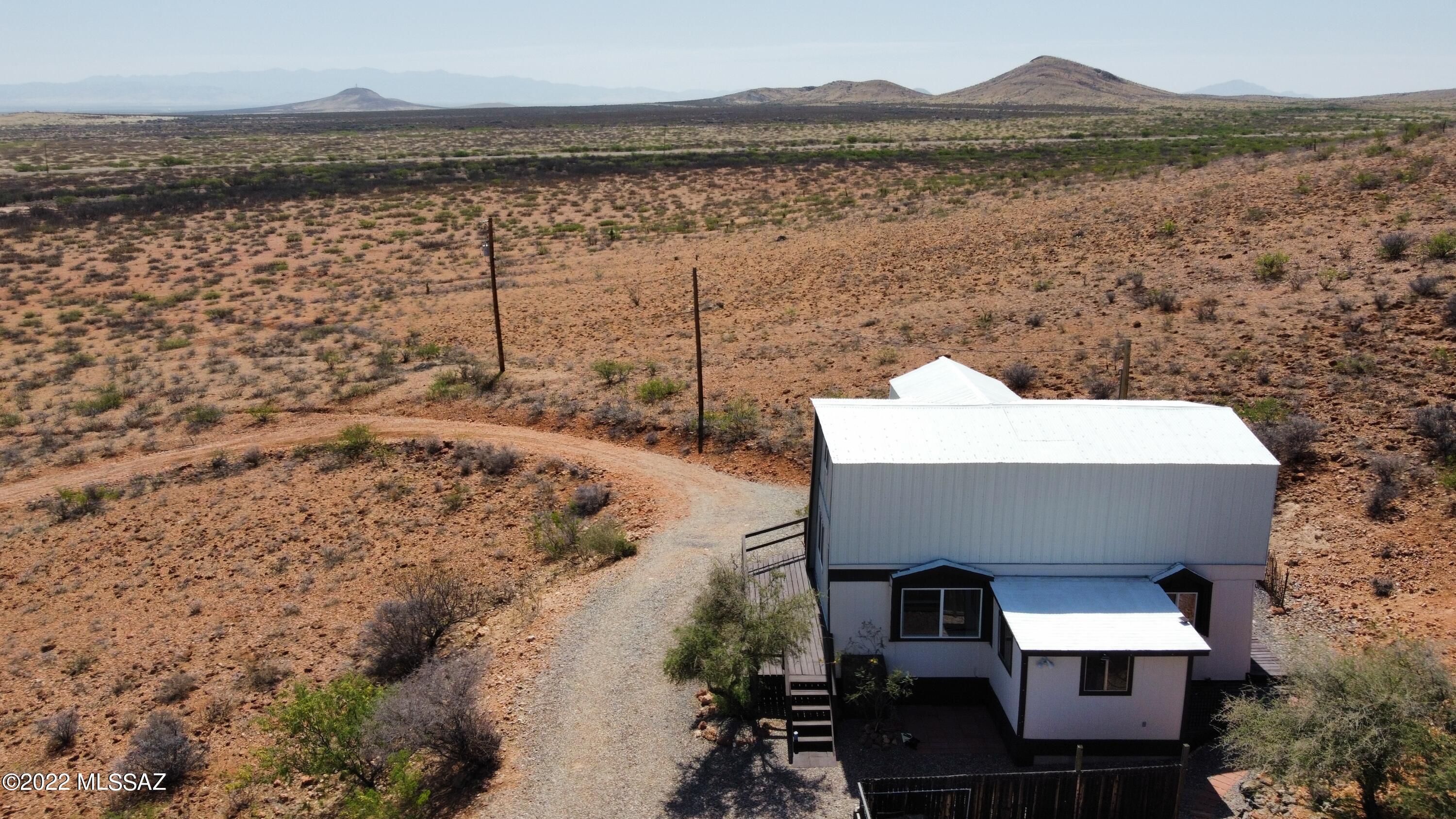 This immaculate two-story hillside cabin sits on 10 acres and offers breathtaking views of the Chiricahua Mountains and Sulphur Springs Valley. The main home features 2 bedrooms, 1 bathroom, a welcoming living area, a kitchen, and a laundry space, plus a separate entry office and a screened porch. Recent improvements include all-new windows and doors, updated bathroom fixtures, a new well pump and pressure tank, new cooling and heating units, a new roof and siding, and an entire repaint. A new foundation was  poured, adding lasting value. Step outside to a wraparound deck perfect for stargazing—set up your telescope and enjoy unparalleled night