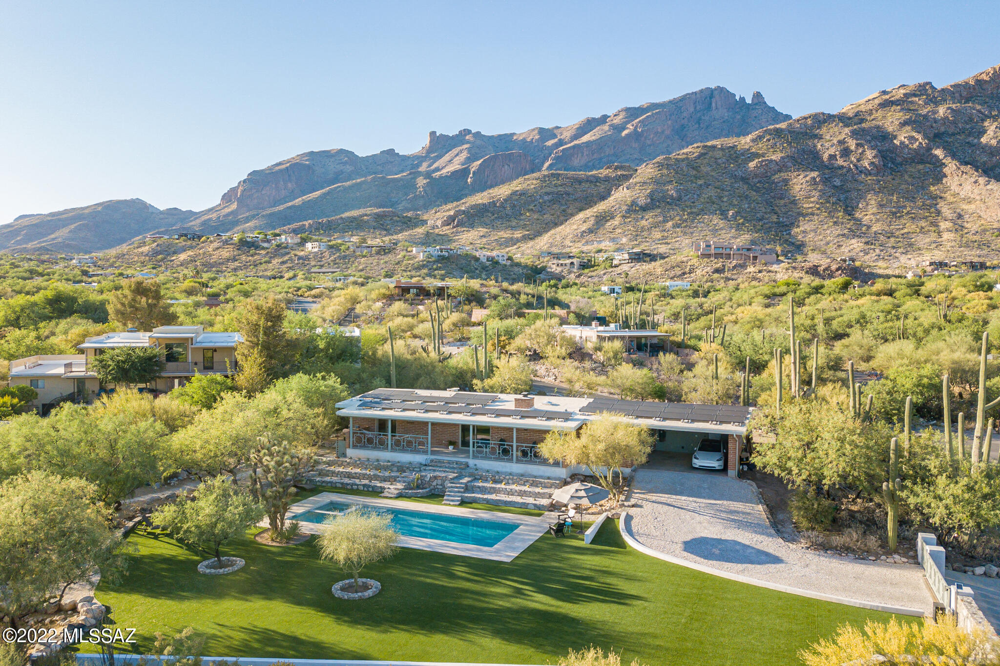 Absolutely stunning 1964 burnt adobe classic in the heart of the Foothills, with the kind of picture perfect outdoor living spaces, views, and visual impact that transcend.  A synergy of natural elements, clean-lined design, and materials that must be seen to be fully appreciated.  Surrounded by hand-crafted native-stone walls, stunning terrain-scaping, and the kind of views that stop people in their tracks, this 3 Bedroom, 2 bath original feels every bit like a slice of paradise, all without losing a shred of authenticity.  Brilliant pool and landscaping transformations feel at once new, yet in complete harmony with the original character of the home, the mature trees, and the natural desert foothills surrounds.  See extended description, virtual tour, and full aerial/walkthrough video. With care taken not to alter the original aesthetic of this mid-century gem, the exterior spaces of the property have undergone a complete transformation, elevating them in every way.  An absolute knockout, aesthetically, but more than that--a home that lends itself to the enjoyment of nature, friends and family ... and moments of quiet solitude inside and out.  As good as it looks in images, it feels even more special in person.  
What's remarkable here is that, as a property in this market, it represents a rare opportunity to enjoy a huge and perfectly executed outdoor space in the heart of the upper Foothills without having to take on the "too-big" house that often goes with it.  On a prime spot in the quiet mid-point of beautiful Coronado Foothills Estates, only a hundred yards or so down from a neighborhood-owned natural space, it's easy to see why this smartly designed and true-to-its-roots '64, sited on a subtle rise, was the perfect canvas on which to paint an outdoor-living masterwork.  Neat as a pin, with the sublime balance of wood beams, burnt adobe, and clean white walls in every space, an interior that could live just as it is for years to come, or be updated with only minor adjustments.  On the outside, an acre transformed: with white travertine, emerald turf, and native stone walls, all working perfectly together to create a feel unlike any other...a pitch-perfect combination of surfaces, color, and reflected light at all hours of day.  
And while this one of those special places that impress at every hour, it's late in the day when it takes on a character that sets it apart.  In the golden hours of the late afternoon, whether looking back at the clean lines and warm texture of the adobe, or catching the glow of the mountains at sunset, cast down onto the emerald turf, the crushed white quartz borders, and the expertly crafted natural stone walls, one really does get the sense of stepping across the line, into the original architect's sketch, as they might have imagined it one day could be...almost like the light, the color, and the vibrancy of it all have somehow blurred the line between the visualized and the actual.
A metamorphosis has occurred here, maximizing the usable space (and there's so much of it here on this 1 acre lot), and managing to do it smartly at every turn.  The walls and terrace abutments were expertly constructed by accomplished local artisans, using rock excavated from this very lot -- in accord with the revered southwest tradition of sourcing materials on-site, the walls are literally of this place.  The choice of surfacing materials, too, combines for an effect on the eye and the living experience that is at once dazzling, with reflective travertine walkways and crushed rock borders, and soothing, with the slow track of palo verde and mesquite shadows across the verdant turf play areas combining for a magical effect.  A showplace at all times of day, the backyard takes on a character all its own in the afternoon hours, as the mix of sunlight and shade make for a slow-moving tapestry of green and gold light.  
The front, north-facing upper yard, too, is special in its own right -- with an orientation toward towering mountain vistas, and semi-elevated above the seldom-trafficked street to the north.  The views, light, and sense of place here in this front walled garden are perhaps the most dramatic in the first few hours of the day, when the early morning sun crests the ridges to the east, and filters down through the canyons and towering saguaros.  
While the immediate attention-getters are the pool and garden spaces, and the classic combination of burnt adobe and overhead beams and planks inside and out, perhaps the real star of this place might be the breezeway.  This breezeway is aptly named, with the north-south axis of this outdoor living space perfectly situated to funnel in surprisingly consistent airflow (not to mention its nearly perfect orientation up toward Finger Rock).  This indoor-outdoor space, a hallmark of mid-century design, lives like a family room, with over 300 sqft of covered patio space in the sheltered area between main home and carport that serves as the hub of morning through evening activity year-round.  Even in the heat of the summer, the volume of air that naturally passes through this north-south oriented passage makes it comfortable enough to entertain, dine, work-from-home, or just sit and enjoy either of the views.  
And what views they are.  From the concrete-topped patio table at its south end, a perfect place to overlook the pool, the emerald green landscaped play surface, and the Santa Ritas far to the south... all while enjoying a meal, working from home, or watching the last hours of the day unwind through the trees with friends.  And on the north end of that space?  One of the best views of Finger Rock you'll find.  From dawn 'til dusk, an ideal spot from which to enjoy the ever-changing interplay of light and shadow across the Santa Catalinas.  The space is perfectly suited for an outdoor living room set, and visitors who come calling won't be blamed for settling here for conversation and never wanting to go further.  And there it is, really, in this unassuming pass-through: a design concept made reality, where the space enhances the daily experiences of the people lucky enough to live in it. 
The amount of time and life that have been spent "out here", and the pure enjoyment that this space lends itself to can not be overstated.  It is the hub of the wheel, connecting the lives of anyone living here... to Beauty, with the stunning views to the north and south ... to Joy, with the easy ability to host and play with friends and family in upper or lower yards... and to Function, as the connecting point between kitchen, laundry, office/storage, and carport.  Rarely does a space that could in most cases be regarded as just a through-way become the integral space that this breezeway does.  But with its combination of views, flow, and the kind of natural but gentle downslope foothills ventilation that makes this space comfortable year-round, this seemingly unremarkable space is quite the opposite.
The 12.5m (41') salt water swimming pool is as well-suited for serious lap swimmers as it is for entertaining and leisure.  Reimagined and resurfaced in 2021, with an inset spa in the NW corner, and surrounded by a relatively-cool-to-the-touch travertine paver surface deck, it's not hard to imagine this being the center of activity in the extended swimming seasons.  (But as comfortable as it is, it's the kind of pool that one might enjoy just as frequently from the dry side.  It is gorgeous on it's own.)
Custom metalworks form the patio railing, and frame views from the patio, as well as tie in with the visual screen that separates breezeway and kitchen from carport.  A circle-in-square design inspired by the carport wall's original breezeblock, it adds just the right amount of geometry, without being obtrusive, painted as they are a soft gray-green tone.  A design element that rings true to the homes modern roots, with a nod toward a Palm Springs vibe. 
Beyond just being aesthetically pleasing, though, this home is future-oriented in the long-term, with roof, gutter, and solar systems having all been added or improved in the last 2 years.  Atop the roof, itself silicone-coated in Fall 2020, sits an impressive 37-panel PV solar array, newly installed in 2021, and generating about 10kwh, enough net capacity for the home's daily needs over the course of a year.  The solar array has been enough to power not only the house's daily electrical needs, but that of the pool, heating it and extending swimming on-demand into the shoulder seasons with an efficient electric heat pump.  Lastly, but notably, especially in the current economic climate, the PV array has excess capacity to have powered a very busy-family's daily driver (through a dedicated 500w charging circuit in the carport).  While the full use of car charging, HVAC, and pool pump and heating can outpace the generation capacity of the PV array in certain months, the credits generated through the system throughout the year provide a net positive balance of power generation between use and PV output.  Notably, too, though the current HVAC split system uses a gas furnace for heat, the PV array was installed with the thought that at some time in the future the heating and air conditioning could be a purely electrically-powered system, and that between pool, pool heat, HVAC, car charging, and everyday use, the entire household's energy needs could be covered by the net production of the solar array.  New gutters and downspouts, installed in 2021, efficiently carry water away from the fascia and the walls, while blending seamlessly, visually, and preserving the home's streamlined look.
And yet after having said all that, there are things yet unmentioned: the solar-powered sliding remote control drive-entry gate...the bonus office space off the carport, with unexpected mountain views...the number of towering saguaros, glowing with perfectly cast landscape spots and floods as the daylight fades...the water-sensible plantings, designed thoughtfully toward a native-water-only need level by 2023...A dining room space, with a picture-perfect framed view of the Santa Catalinas....the smartly designed back patio, which is oriented just perfectly to catch full sun all day in the winter, and cast a warming effect into the house in the coolest months, yet provide deep shade from the sun in the hottest times of year.... a free-standing and custom-finished self-contained "Farm Wall" vertical garden system, on which grow towers of Basil, Kale, Arugula, Bib Lettuce; all with surprisingly little effort and upkeep.   
All in all, an absolutely remarkable property.  The photos and video, as stunning as they are, do not adequately convey the feel of it all, especially late in the day.  An incredible place.