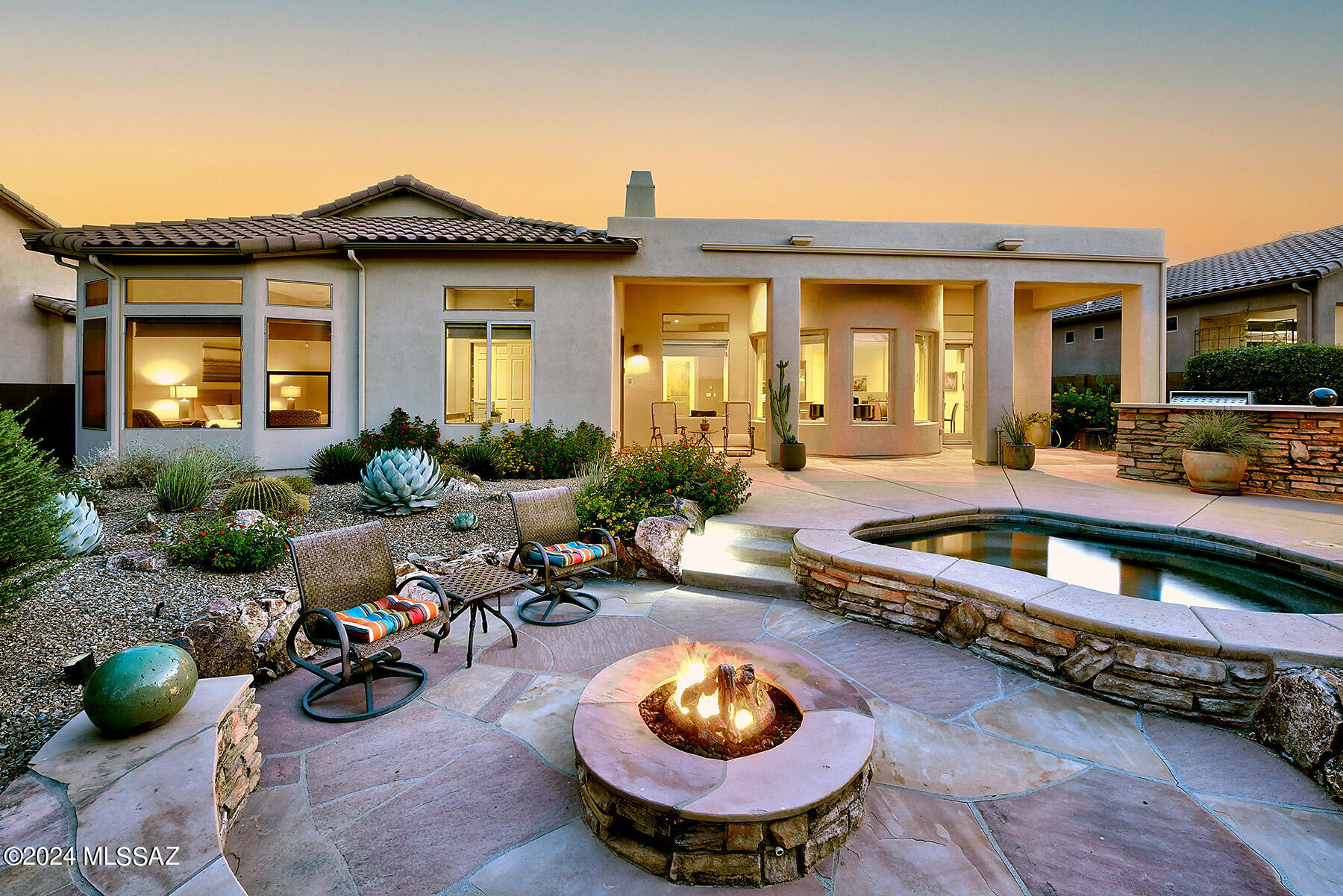 Nestled within a serene gated community in Oro Valley, this exquisite home offers a rare blend of privacy and natural beauty. Situated on a premium lot that backs onto the tranquil Vistoso Nature Preserve, every aspect of this property is designed for the most discerning of buyers. Step into your own oasis, where lush landscaped gardens surround a large spa and a cozy gas firepit, perfect for unwinding and birdwatching in peaceful solitude. A charming front gated courtyard adorned with lovely fountains invites you to savor your morning coffee amidst the soothing sounds of nature. Inside, the heart of the home is a beautifully remodeled kitchen featuring quarter-sawn oak refaced cabinets, elegant quartzite countertops, and top of the line appliances. With a spacious bar seating area and a casual eat-in space, it seamlessly flows into the open great room, ideal for both daily living and entertaining. Large picture windows frame breathtaking views of the majestic Catalina Mountains, while a spacious dining area and wood mantle stone fireplace create a warm ambiance. Gorgeous tile flooring throughout adds a touch of sophistication and ensures easy maintenance. The primary suite is a sanctuary unto itself, boasting a tastefully remodeled bathroom with an elegant soaking tub, dual vanities, a separate shower, and double closets. Two additional guest rooms share a newly renovated bath, while a fourth bedroom functions as a private guest quarters complete with its own full bath. For those who enjoy versatility, the flexible floor plan offers endless possibilities,  including a heated & cooled single garage currently used as a home gym. Additional 2 car garage has epoxy flooring and ample storage.  A huge laundry room with cabinets and a new sink provides added convenience. Additional features include a newer water heater, water softener, upgraded lighting, and a smart irrigation system, ensuring comfort and efficiency year-round. Outside, the expansive yard beckons you to entertain under a large ramada, soak in the spa, and gather around the gas fire pit to marvel at stunning sunset views over the mountains. Easy access to a near 6-mile cart path provides delightful walks, while a built in BBQ invites you to host cookouts and enjoy living at its finest.