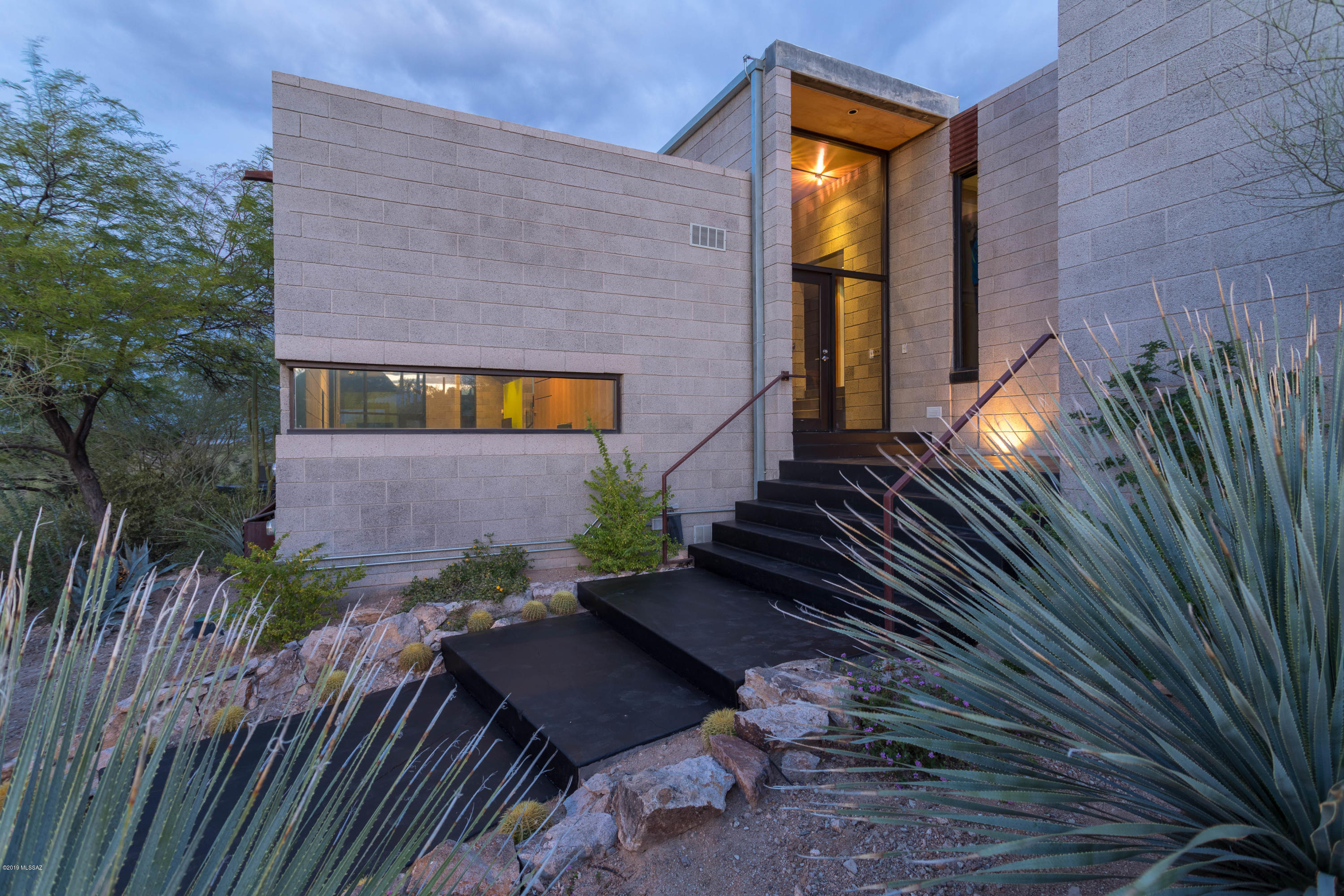 Award-winning modern architecture by Ibarra Rosano! Commanding views of mountains/city lights! Spectacular desert home/super-livable design: guest bedrooms and bath with split master suite is separated by a glass corridor and includes a flex space; perfect as office/work out area. Great room aligned toward remarkable view of the Catalina Mtns/City lights. Timeless desert modern materials: sandblasted Integra block, raw steel, glass, birch millwork and finished concrete floors. Outdoor view terraces and patios, oriented around a stunning pool and spa. Native landscape/mature arid trees provide shade and drama; synthetic lawns and Solar Array add efficiency. Gated 2.25 acre site includes 2-car covered carport, stable and more. A masterpiece of design, irreplaceable at the asking price.