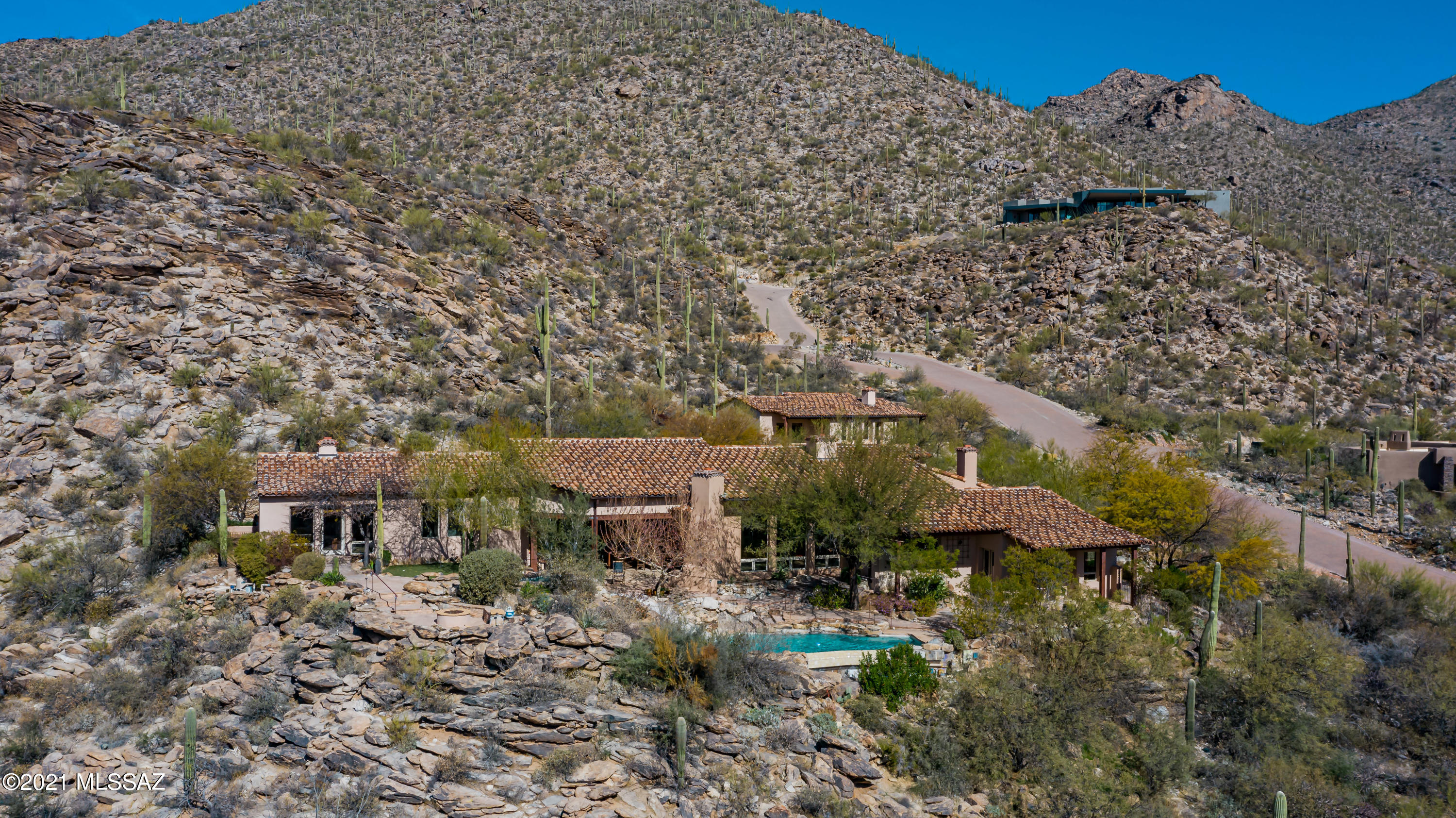 This magnificent estate sits on 1.82 acres in guard gated Canyon Pass at Dove Mountain. Unparalleled mountain & panoramic city light views. Highest quality construction w/stunning architectural accents throughout the home which include wood beamed ceilings, expansive picture windows, tumbled travertine and hard wood flooring, alder doors & 6 fireplaces! 
Designed by renowned Tucson architect Gary Robison, this home is ideal for a family with a love of entertaining friends and family.  From the moment one enters the custom iron and glass entry doors and is greeted by a sculptured wall of water gently cascading over a natural stone backdrop, the special nature of this home is abundant.  The great room features a grand fireplace, high beamed & planked celing and walls of windows. The gourmet kitchen includes granite counters, designer stainless steel appliances and a fireplace. Back patio offers a fireplace, an outdoor kitchen, infinity pool w/rock water slide, a spa, a shower, fire pit w/mesmerizing views & a putting green.
Each bedroom includes it's own beverage refrigerator drawer, build in dressers, closets plus the rooms are separate with abundant privacy.
Designed to accentuate the stunning mountain and city lights views from multiple panoramic windows, every window is a work of art from which one can watch glorious sunsets and a parade of local wildlife at dusk just beyond the home's perimeters. A large formal dining room sets the stage for fabulous dinner parties yet remains intimate in feeling, with built-in buffets and window seat and a private terrace just out the door. The kitchen includes all that a great cook could dream of: rich alder cabinetry, coffered ceiling, 6 burner Dacor cooktop with potfiller, 2 Dacor wall ovens, 2 warming drawers, Sub-Zero built-in refrigerator and two refrigerator drawers, sink with a view plus prep sink, island seating at a beautiful granite counter, Dacor dishwasher plus Fisher-Paykel dishwasher drawer for those small loads, icemaker and an elegant wood-framed wine refrigerator accommodating at least ---- bottles, and generous pantry. And don't miss the charming corner fireplace. In the great-room, centered on a massive fireplace and a built-in TV cabinet, one can be as formal or relaxed as fits one's style. Enjoy panoramic views in every direction, under a planked wood ceiling accented with wood beams. The adjacent breakfast area includes a wet bar and looks out to a pond and waterfall feature set into the surrounding stone backdrop. The master suite is truly a suite: the large bedroom includes a generous sitting/living area with fireplace and walls of windows, two refrigerator drawers , with a spectacular master bath featuring a steam unit and bench in shower area, separate w/c with bidet, a Jacuzzi tub overlooking gardens, and a Dacor towel warmer for those chilly desert mornings. A richly appointed walk-in closet and separate laundry room complete the master suite. 

The laundry room has hanging space for closet overflow, raised W/D and sink. A substantial office is just down the hall, featuring a handsome built-in desk and drawers, bookshelves galore and an en-suite full bath. 

The second bedroom is a spectacular guest suite with its own beehive fireplace in the sitting area, wet bar with sink, full bathwith seated make-up area and private terrace. The spacious main laundry room includes raised Asko washer and dryer, sink and a 2nd refrigerator.

Stepping outside from the great room is an outdoor living area with TV, another cozy fireplace, banquette seating and a full outdoor kitchen, all sheltered under a rich wood beamed ceiling. Beyond is a salt water infinity pool and spa snuggled into natural rock formations, with a concrete water slide in to the pool for the grandkids should they be visiting. A putting green is off to the side of the pool. A firepit with seating is built into a rocky promontory looking out to forever unobstructed views of the Valley below. The adjacent 1613 sq. ft. guest home is accessed by a path along a flowing water feature and ponds built into the rocks, and is in fact a small home. It includes a full sitting area with fireplace, complete kitchen, laundry room, and two bedrooms with en suite baths. Included features to note are the built-in vacuum systems in both the main home and guest home, the extensive built-in cabinetry throughout the home, the use of the highest quality materials with a focus on natural materials, and wood-framed windows throughout. This is a home for those of the most discerning taste and sophistication, and will provide great shared moments for years to come. 

Home may be purchased turn-key with furnishings, accessories and artwork (home and guest house) for an additional $50,000.