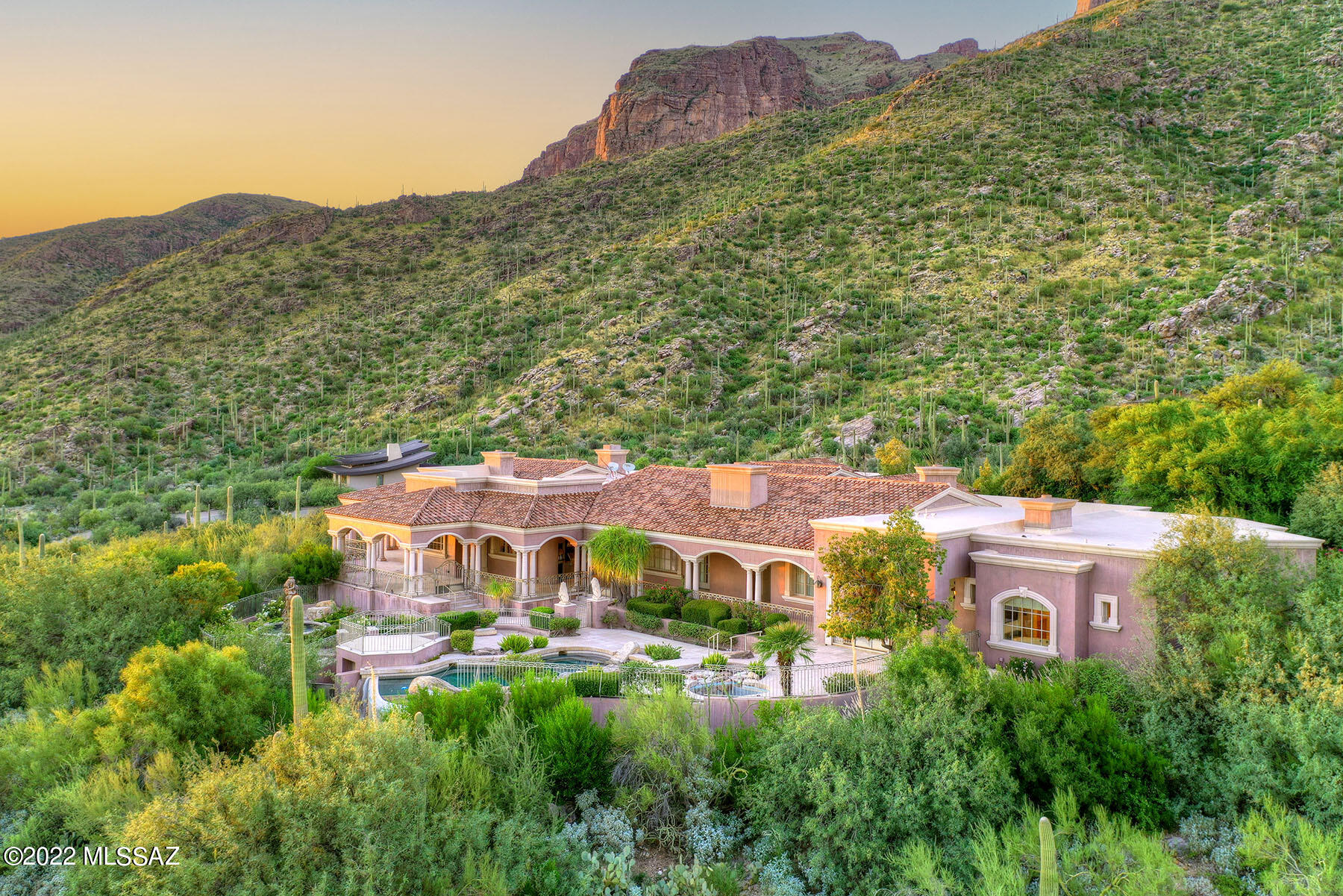 This spectacular, 13,320 sq. ft. all-masonry stucco mansion is nestled in prestigious, gated The Canyons at the north end of Alvernon Way on a 1.35-acre lot and offers sweeping city, mountain, sunset & sunrise views. The 10,372 sq. ft. main level (with no steps) features 5 bedrooms, each with an en-suite bathroom. The elevator (an exact replica of the Beverly Hills Hotel ''Pretty Woman'' elevator) or staircase takes you to the 2,948 sq. ft. lower level includes a full guest quarters with living room & kitchenette, a wine room, and a gym with a sauna & a tanning room. Also on the lower level is the 2,158 sq. ft. (heated & cooled) 3-car garage, and a 6,076 sq. ft. (heated & cooled) world-class 16-car auto showroom with auto turntable. Enter the main level foyer into living room/dining room with soaring coved, hand-painted mural ceilings, exquisite chandeliers, gold leaf moldings, custom carpets over natural stone floors, 17th & 18th century antiques, walls of windows, a bar, and an imported stone fireplace. The gourmet chef's kitchen includes a main kitchen, a working kitchen and a walk-in pantry. The family room, open to the main kitchen, features a fireplace and access to the covered patio. The spacious billiard room/pub offers custom cabinetry, a full bar, a fireplace, and a 15-seat movie theater (designed by Theo Kalmirakis of New York), evokes the ambiance of a New York City art deco theatre. The office close to the primary bedroom offers custom carpets and Clive Christian custom cabinetry. The primary bedroom offers a fireplace and a luxurious bathroom complete with dual walk-in closets, a second laundry room, dual vanity, a spa tub and a fireplace. Enjoy the beautiful outdoor living areas including an expansive wraparound porch, fountains, a pool/spa, an outdoor kitchen, and dramatic city & mountain views. This home is ideal for a large or multi-generational family, for a hobbyists, a car collector, musicians needing professional studio space, etc. Incomparable quality in an incomparable subdivision on an incomparable lot!