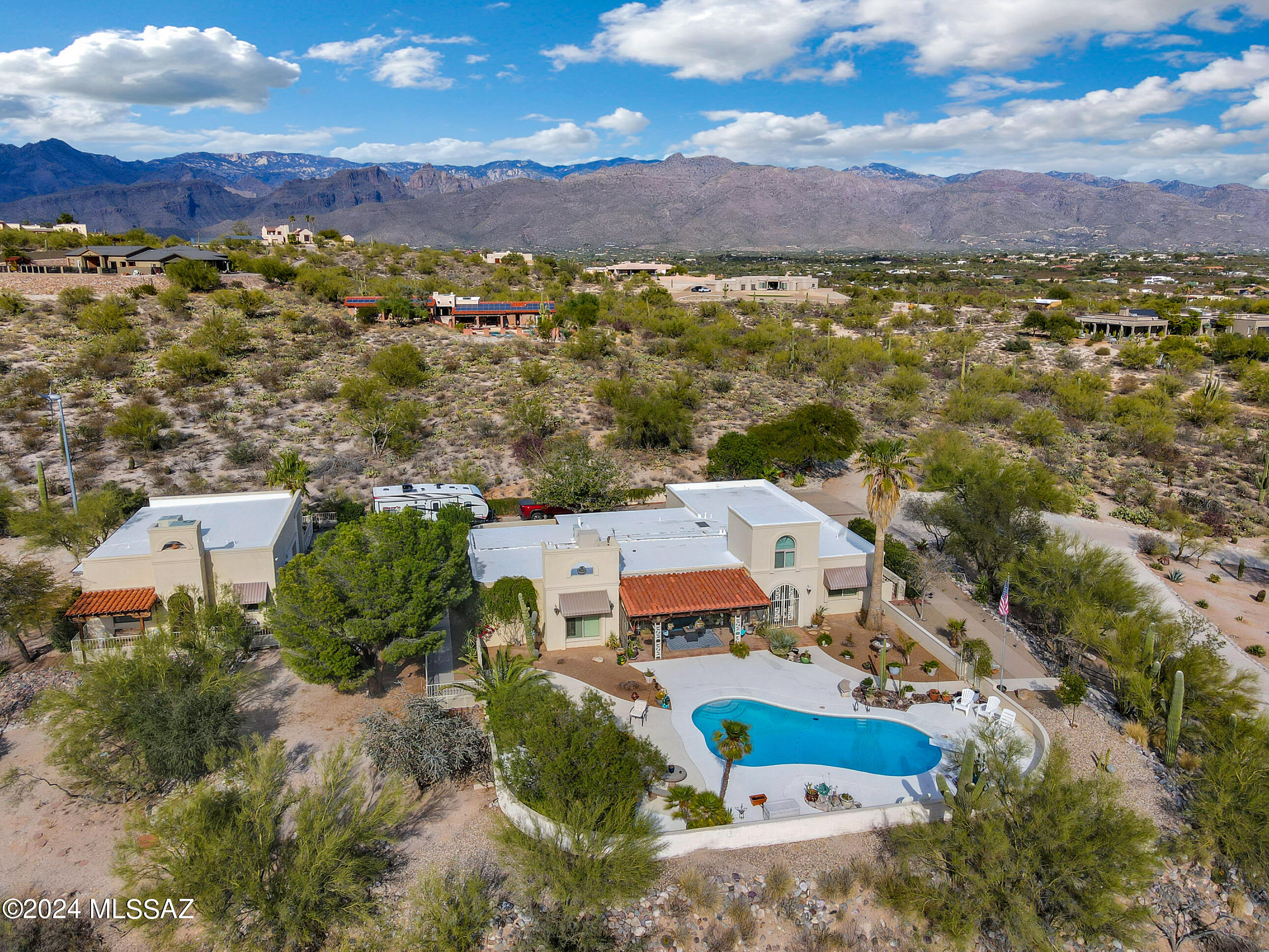 Stunning masonry constructed home on hilltop boasts panoramic views of the mountains and twinkling city lights. Privacy abounds from this serene desert setting on 5.31 acres. Inviting gated entry with  pristine landscape driveway welcomes guests to this charming desert oasis. Exceptional  4 BR/2 BA home offers a split floor plan and great room design. Architectural details include: high wood beam ceilings, brick fireplace, loft, gracious room sizes and huge picture windows with captivating views in all directions.. Enjoy delightful outdoor living spaces with sparkling pool, firepit and covered patio to take in the sunset. Remodeled with tile throughout. Deluxe kitchen has SS appliances, warming drawer, pot filler and abundant cabinetry. Casita offers 1 BR/ 1BA + 3 car RV garage/workshop.