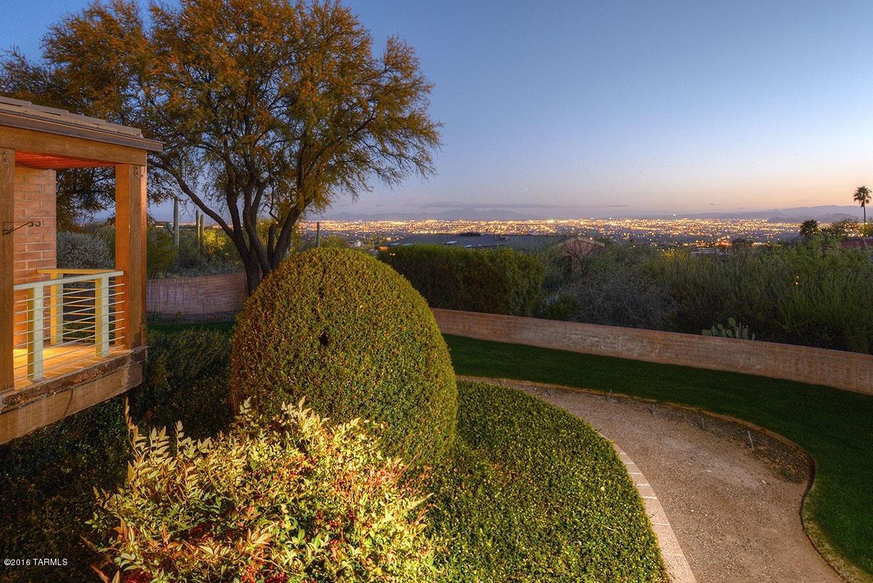 Formerly known as ''The Coors Estate'' this home sits high up in Cobblestone on a double lot and is handicap accessible. Wonderful vistas of Catalina Mtns and sparkling city lights. This home has beautiful wood floors, floor to ceiling windows, an extensive covered patio system around most of the home, over 3,773 sq ft. Indoor pool with heating and cooling. Commercial construction of Steel I beams and copper gutters.