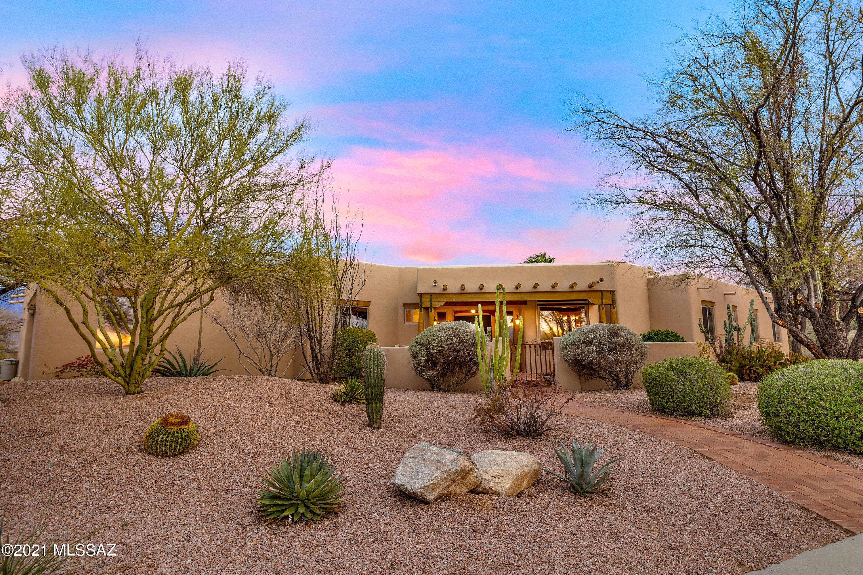 Stunning Sante Fe home with panoramic mountain views located in the heart of Oro Valley. A true, custom home with all the amenities, this property features 5 bedrooms, 3 baths, multiple living areas, and a separate office off the freshly painted and epoxied garage. Sunlight abounds inside with skylights and large windows, perfect for enjoying sunny Tucson days. True Santa Fe charm in pristine condition, featuring vigas, a bee-hive fireplace, and flagstone floors, along with new interior paint. The chef's kitchen features a large Sub-Zero refrigerator and professional range. Enjoy 360 mountain views of the Tortolita and Catalina mountains from the elevated, corner lot. Step into the backyard oasis, an entertainer's dream, featuring a saltwater pool, hot tub, fireplace and outdoor kitchen.