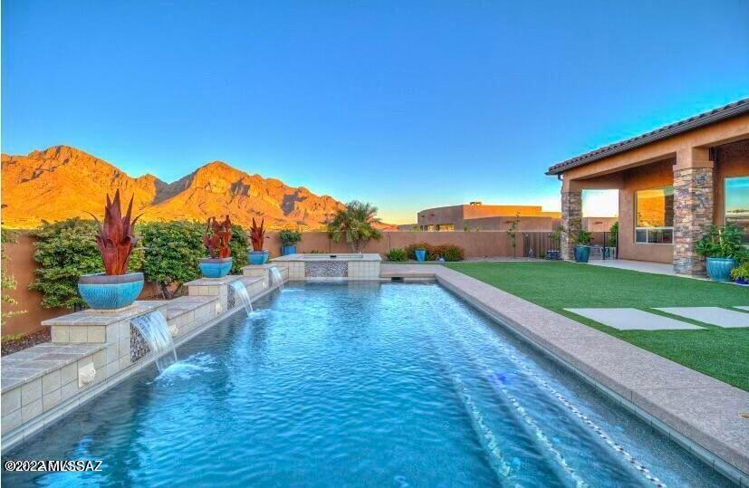 Stunning contemporary masterpiece located in the rarely available neighborhood of River's Edge in ORO VALLEY! This home has ALL the sweeping VIEWS one could hope for, from every corner of the resort style back yard! Situated on a one-acre view lot, the majestic presence of Pusch Ridge and the Catalina mountains will truly take your breath away. As you enter the open and modern, split floor plan, the great room with soaring 15-foot beam ceilings and concrete look tile will leave you speechless! Immediately you will notice the Catalina's from every corner of the open floor plan through the picture windows and backyard oasis. Enjoy panoramic views from the full-length covered patio with radiant heaters for year-round relaxation. The geometrical pebble tech pool and spa, along with artificial turf, built in bar and BBQ are perfect for entertaining as the water features provide soothing sounds in the background. This home is also fully automated with surround sound in every room.
The gourmet kitchen boasts double dishwashers, gas stove, microwave/convention combo and wall oven, warming drawer, island with prep sink, walk in pantry, wine fridge, and wrap around bar with granite counters. The primary bedroom is located separately from the other bedrooms and den. The Spa-like retreat features picture windows, custom tile work, quartz countertops, large walk-in shower with sleek design and custom-built closet. Additionally, there is a den off the entryway and two bedrooms including one with an en suite located on the opposite wing of the home. Don't forget to notice the large laundry/mud room and oversized three car garage to provide ample storage! Homes in this neighborhood are a rare find and will not last!