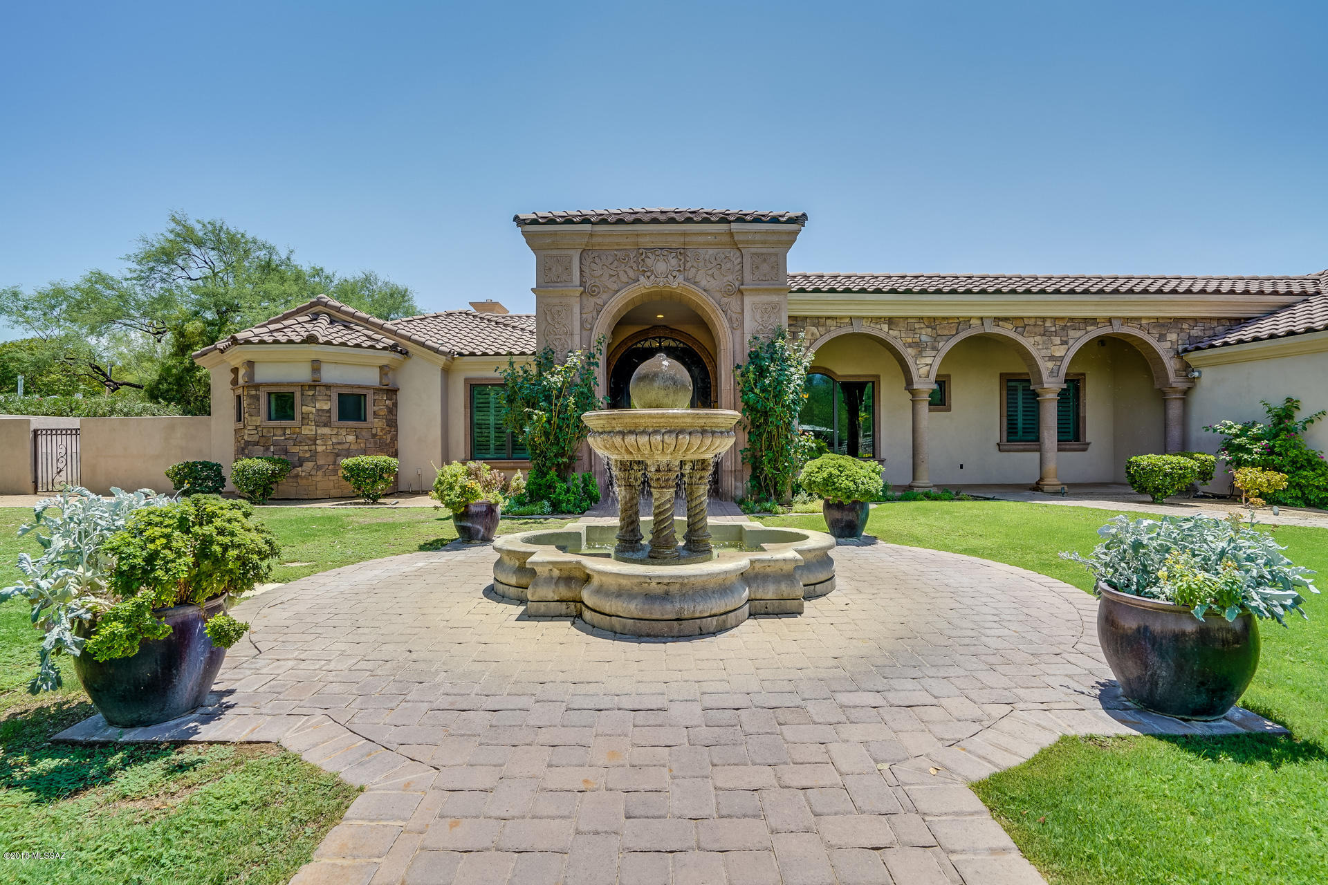 The entrance with an exquisitely carved cantera stone fountain, unique wrought iron designed gate and entry door, trees for privacy and views of the Catalina mts. This house is equally stunning on the inside using the original designed beautiful cantera stone for high columns and surrounds of fireplaces. The 5300 plus sq ft offers spaces for family and friends and needs to be seen to truly appreciate the planning that was accomplished to make this house one of a kind. A master bedroom opens to the pool, circular shower, lounge in the spa Toto tub and watch TV Adjacent to the MB is a fabulous exercise room and study. Privacy for patio living with pool, barbecue, sport court to enjoy our Az life style.