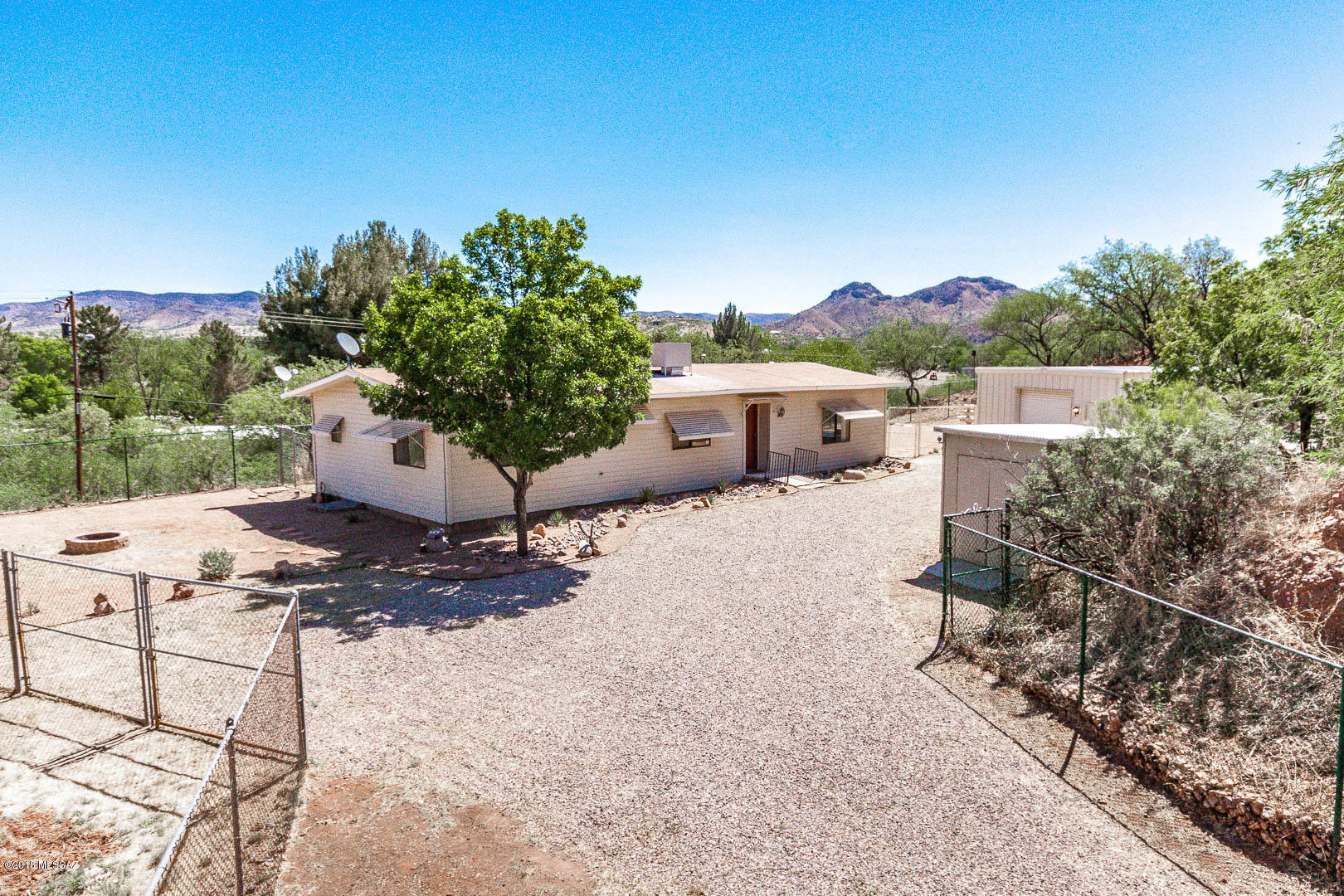 UNIQUE, PRIVATE FAMILY COMPOUND right in the Town of Patagonia. Sitting on .6 acre, completely fenced and gated for privacy & security.  Inside the compound are currently 2 mfr homes, a garage, workshop, 2 storage units, & small greenhouse. There is room for dogs and/or a large garden or even additional structures. Main home is 1536 sf, 3Bd/2Ba and has been extensively repaired/remodeled. There's a large living/dining room w/built-in cabinets, airy kitchen freshly painted w/new tile back splash, & laundry area next to the kitchen. The older single wide mfr home is clean & livable but would benefit from repairs & updating. Also on the property is a spacious metal garage, an old greenhouse, a workshop w/plumbing & electricity and 2 storage sheds. This property has enormous future potential!