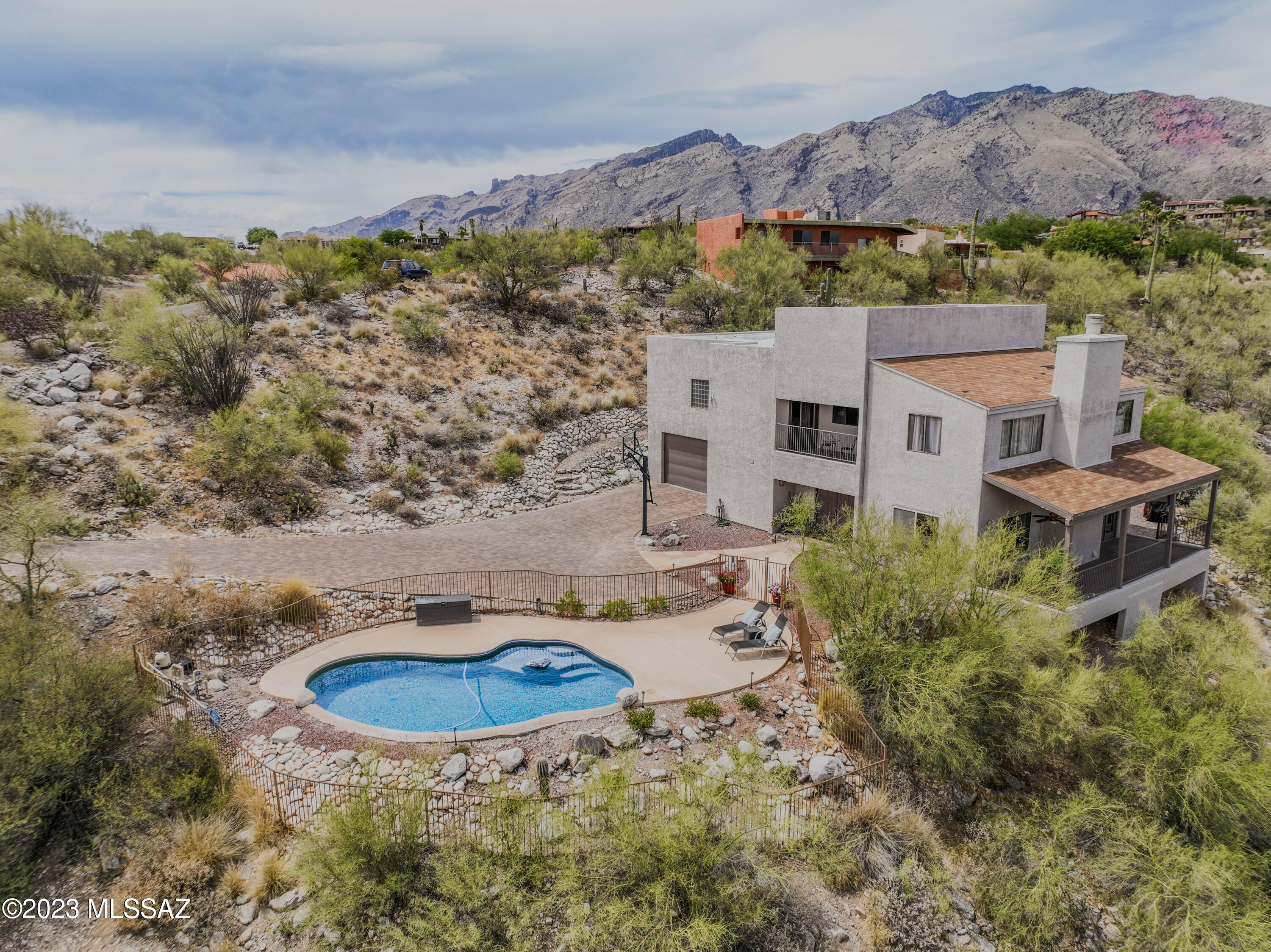Enjoy dramatic mountain views by day, poolside city lights by night! A brick paver driveway leads to this custom, foothills, hillside home overlooking the natural desert w/mature Saguaros and trees. The island kitchen boasts custom hickory cabinets w/pull-out shelves, smooth surface cooktop, double ovens, cafÃ©-style fridge & 2 pantries. French doors open to 1 of 3 balconies to relax, dine or entertain. The primary suite features a huge walk-in closet, a private balcony, plus an adjoining sitting room or office. The elegant bath includes dual vanities, garden tub, and separate shower. Don't miss the nearly 300 sq ft, first floor bonus rm (not included in assessor's sq ft) being used as a music studio, but could also be a home office, exercise or guest room. Catalina Foothills School Dist