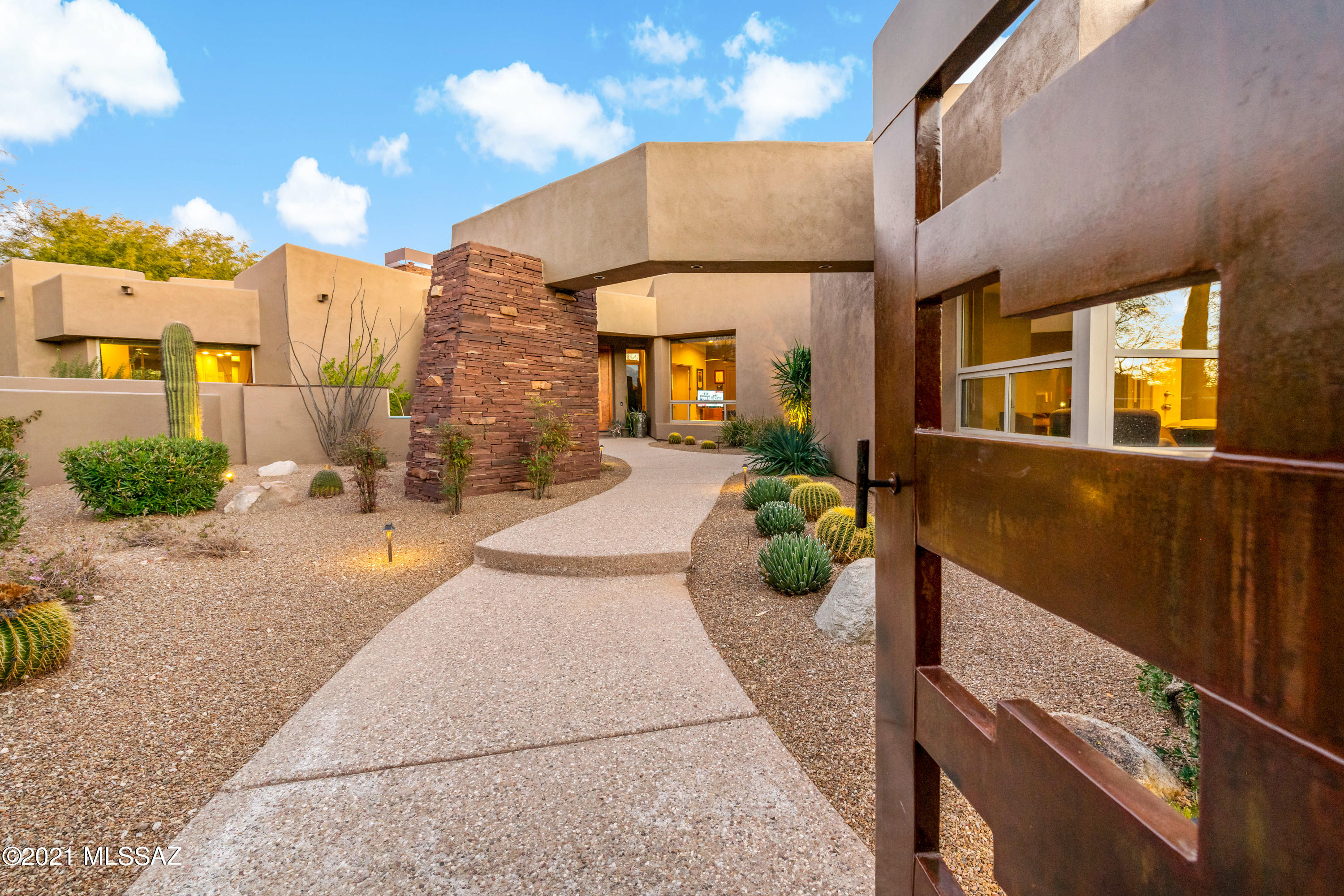 Surreptitiously placed on 1 Acre of wooded terrain, Kevin Howard designed a home that gives you all the spaces you may desire. Circular driveway is lined with massive trees that lead you to a wonderful courtyard 
displaying a copper patina water feature.   Masculine custom front door takes you into a wide open living & dinning room with wet bar. Walls of glass frame the Catalina Mountains. Split floor plan layout is perfect for maximum space and indoor privacy.  Separate Guest House entrance off of courtyard is well spaced for friends and family.  Back yard is perfect for entertaining with large spaces,  oversized Pool & Spa,  Fireplace and Outdoor Kitchen/BBQ.
