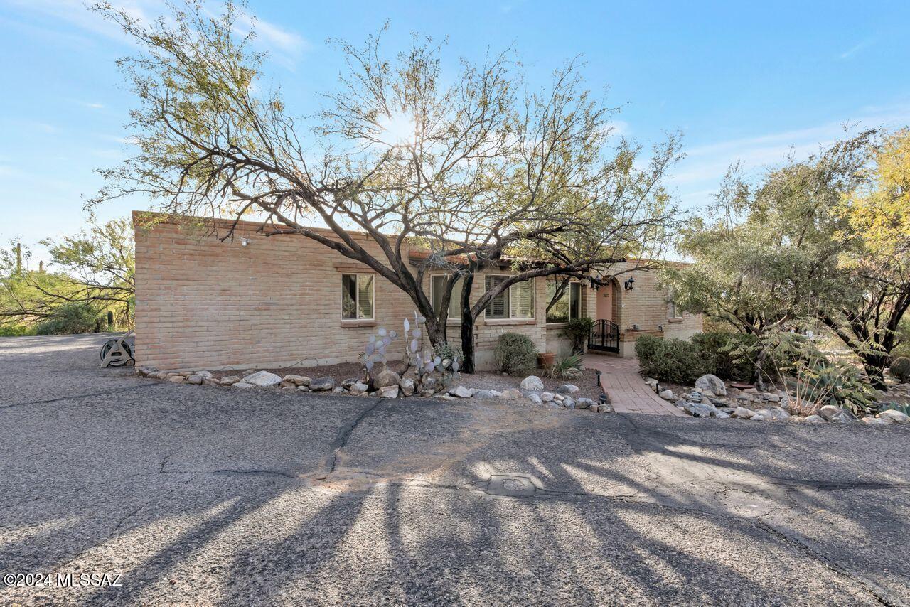 Nestled in the tranquil Coronado Foothills, this classic burnt adobe home offers serene desert living with a private shaded porch/view patio for dining & entertaining and lush yard encircling a sparking pool and waterfall. Enjoy stunning Catalina Mountain views from the comfort of your lovely yard. Features include a cozy fireplace in the living area. built-in murphy bed in one of the bedrooms, and a spacious walk-in closet with custom shelving in the primary suite. Freshly painted with no carpet, this home has a 15 SEER 5-ton HVAC system plus ample guest parking. Extra den/possible office off the kitchen, breakfast nook, and a separate laundry room with sink complete this charming foothills home. Near shopping, trails and Catalina Foothills HS.