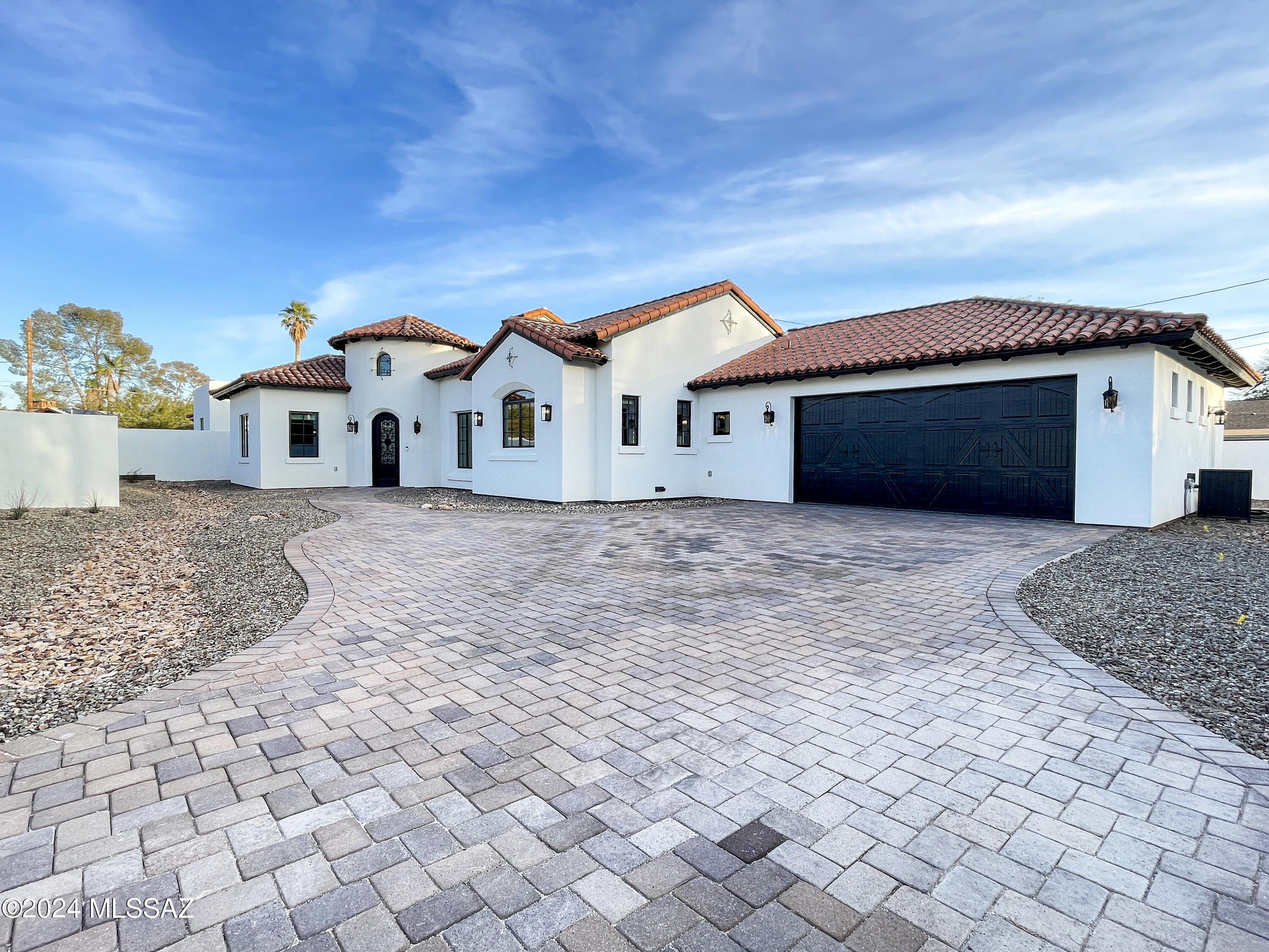 Your private gated new construction Spanish revival style home awaits you in this unique Sam Hughes neighborhood.  Only 8 blocks from the U of A makes this a desirable location.  Upon entering you view an inviting great room with beamed ceiling, visually stunning fireplace wall, scored concrete floors, and a kitchen you can't wait to spend time in.  Wall cabinets provide you with ample storage while the quartz countertop island, harboring the microwave and wine cooler, allows you to spread out and enjoy cooking on your gas stove with stunning vent hood.  Indoor/outdoor living and entertaining is a must with the large paved patio seen through the center opening sliding doors.  Find retreat in the 4 generously sized bedrooms creating unique spaces for all ....(.see more) .... not to mention 3 incredibly designed full size bathrooms. Laundry room is a bright, enjoyable space located near the kitchen for multitasking ease. Garage access also near kitchen and provides its own unique design.  Backyard wraps around on both sides of home with a paved pad ready with electrical in place to add a spa.  Custom features throughout.....don't miss this rare opportunity in Sam Hughes!