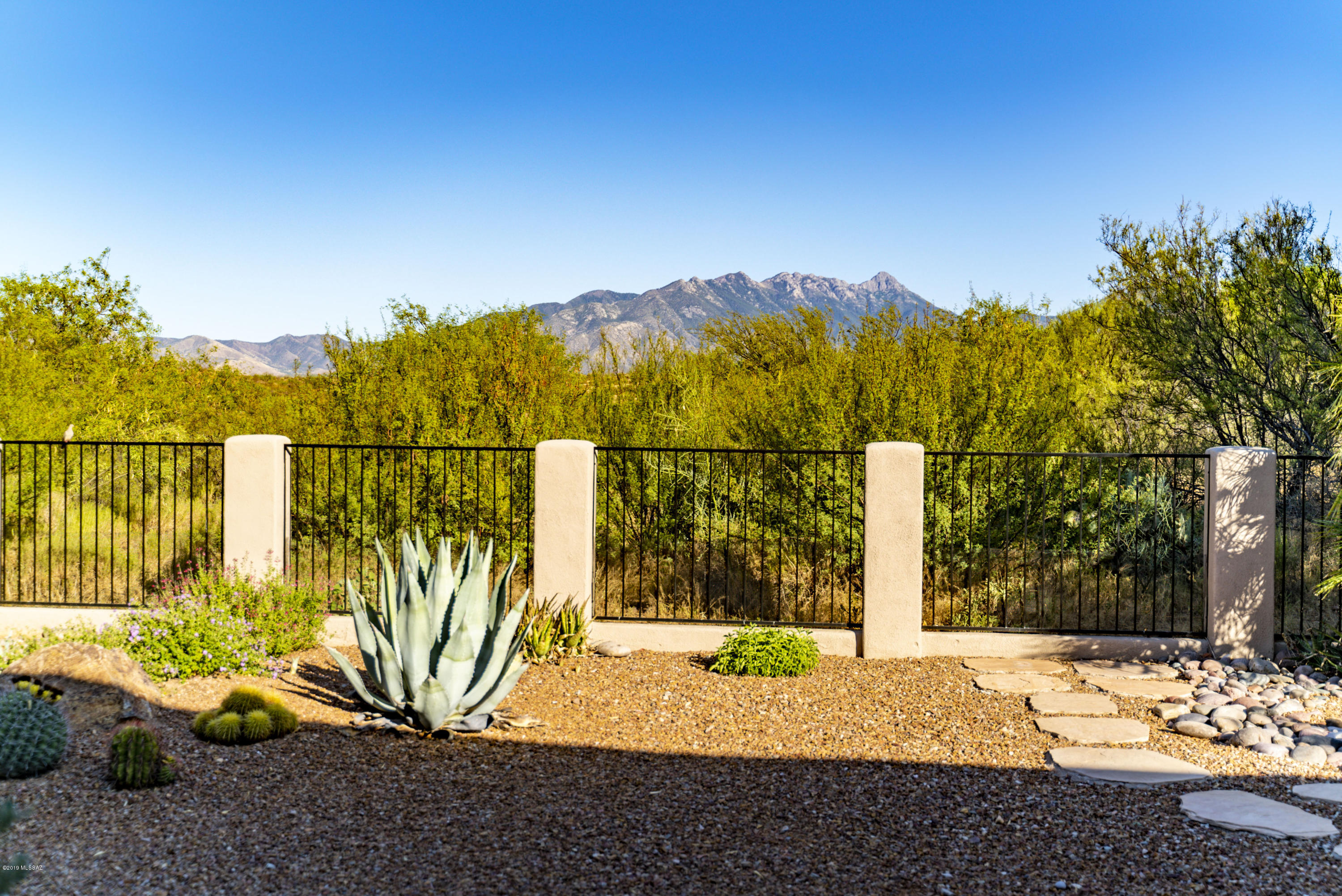 If you are looking for a Santa Fe style home on a private 1.5 acres lot, then today is a great day!  Your fascinating tour is about to begin as you enter through a solid wood door into the foyer where pony walls are crowned in log posts and wood beams capturing the southwest feeling.   A corner Kiva fireplace takes center stage with custom tile work while dual patio doors invite you to a backyard wonderland.  The contemporary architecture in the kitchen will delight your culinary imagination - hickory cabinets, granite counters, stainless appliances and a suspended soffit with recessed lighting.  The adjacent dining area offers wonderful views and easy patio access while a family gathering room is wrapped in glass panes displaying lush natural greenery.  Retreat to your master suite where you'll find a large view window and a wood casement glass garden door leading to the covered patio.  Your luxurious bath features exceptional space, separate "His and Hers" vanities, a tile wrapped soaking tub and separate custom tile shower. Double doors take you into your office where beautiful Saguaro ribbed cabinetry reveals a convenient pull-down Murphy bed for additional overnight guests while the built-in workstation provides patio views while doing computer work.  Relax on your private patio where natures setting provides stunning Santa Rita Mountain views that chaperon in rich indigenous vegetation creating a quiet sanctuary. Stunning sunrise and sunsets that you will never get tired of and star filled skies that will amaze you!