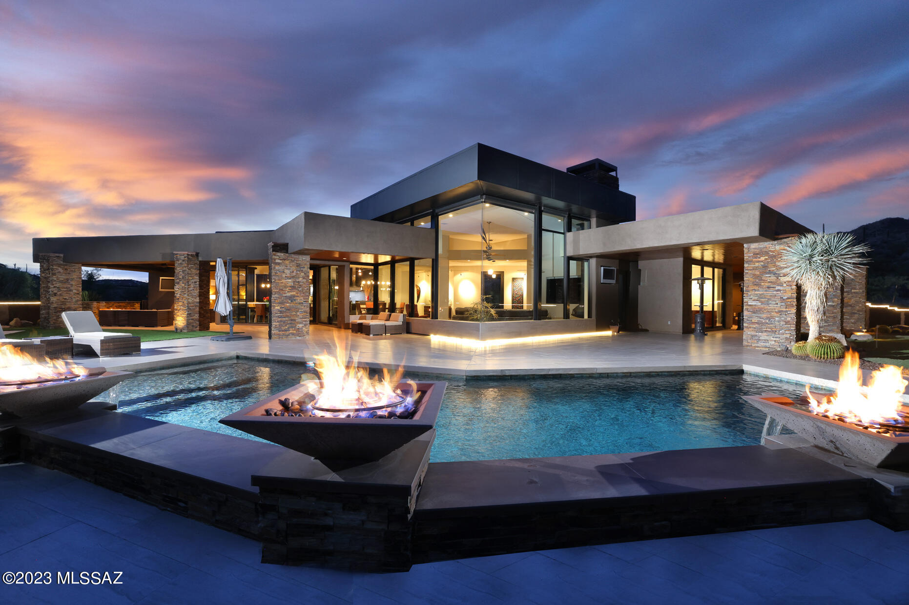 Welcome to this exceptional modern-contemporary in Oro Valley's prestigious Stone Canyon Club; the premier guard-gated golf community in So. Arizona. Featuring elevated panoramic views of the Catalina Mountains and Tuson city lights. The long private driveway leads to the dramatic 25-foot waterfall and beautiful entry. Once inside enjoy walls of glass displaying unobstructed mountain views and extensive outdoor living space. The master suite, secondary bedrooms, and office are all beyond spacious. Distinctive limestone flooring is predominantly featured throughout the home, along with wood flooring in the office, and beautiful porcelain tile for the expansive exterior living space. The gourmet kitchen features Wolf and Sub-Zero appliances. The oversized 3-car garage features an air-conditioned workshop, large storage closet, and epoxy flooring. The outdoor living space features 1,500 square feet under roof, outdoor kitchen, beautiful linear fireplace, built-in hot tub, heated pool with fire and water features, putting green, pool bathroom, and of course the amazing mountain and city views. Additional features include Central Vac, custom lighting and audio throughout the interior and exterior, motorized windows in the great room, motorized interior shades and exterior solar screens, three dishwashers, warming drawer, wet bar, spa-like master shower, stunning powder room, beautifully designed landscaping, and backyard privacy wall lined with porcelain tile. Stone Canyon Club is the premier, private, 24-hour guard-gated golf community situated on 1,400 acres in southern Arizona in the foothills of the Tortolita Mountains in Oro Valley, Arizona. It offers the Jay Moorish Signature Design championship golf course, a luxurious health and fitness facility, a gourmet restaurant and bar, as well as leagues, clubs, and amenities for all ages.