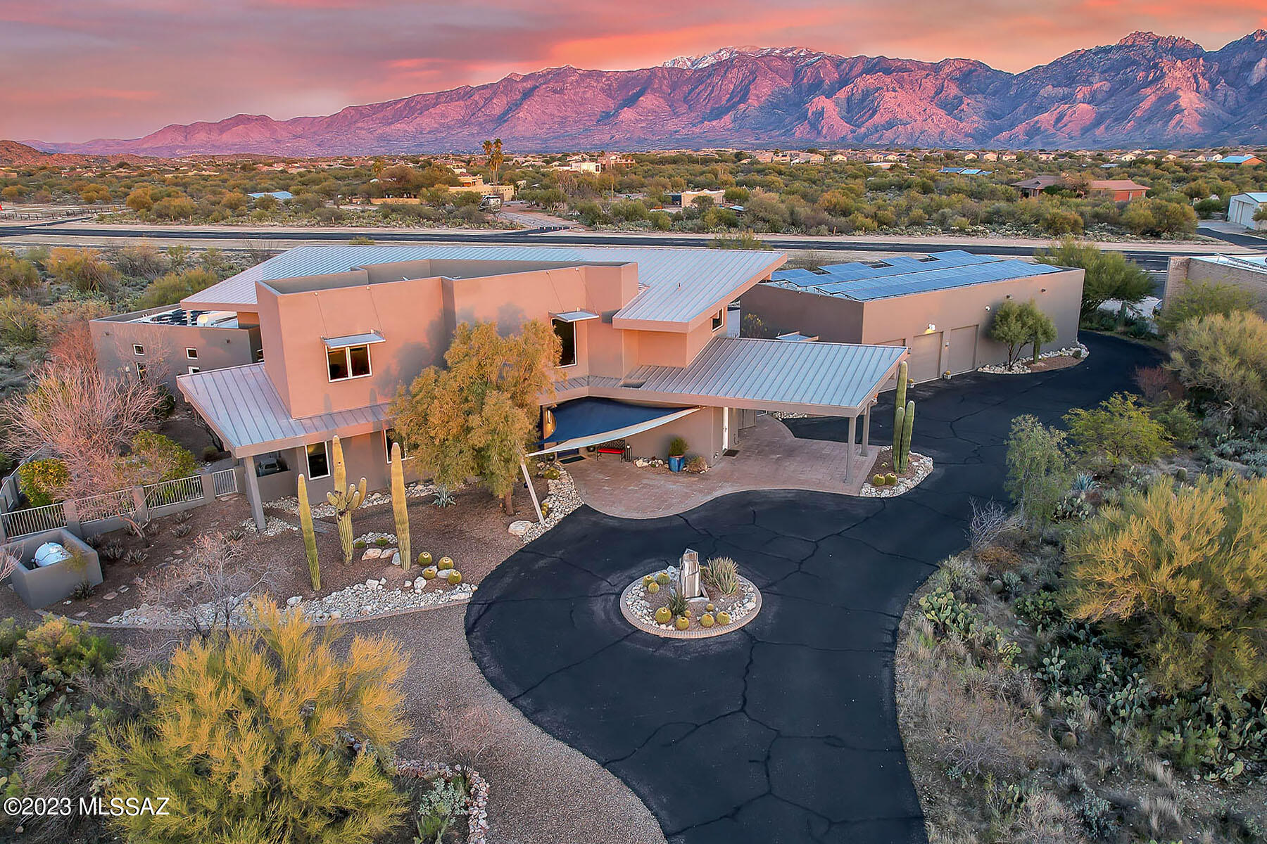 This custom-built home, sited on 7.5 acres in the prestigious La Cholla Airpark, boasts 5078 sq. ft. of luxurious living space, including 4 bedrooms and 5 baths.  The three-dimensional spaces throughout the home feature two-story walls of windows that offer panoramic mountain views from every angle.  
The aviator theme is present throughout the home, from the entry glass to the stair rails and  lighting fixtures.  The polished concrete and tiger-wood floors add to the sleek, modern feel of the home.  The gourmet kitchen off of great room with fireplace features granite countertops and a stainless steel bar height counter with seating for four as well as top-of-the-line appliances.  8-foot-tall solid core doors can be found throughout the home, and the custom stainless steel railings for the loft and stairs feature a unique aviation design.  The contemporary high-end light fixtures throughout the home invoke aviation themes such as wings and clouds.
This home is also an energy-efficient dream come true.  Solar panels provide 92% of the electric energy to the home, greatly reducing your carbon footprint and saving you money on energy bills!
Outside, enjoy the saltwater pebble tech pool with integral spa, perfect for relaxing and taking in the breathtaking Pusch Ridge Mountain views.  The property also includes  a gravel walking trail that winds its way through the property, providing a serene and peaceful setting for nature walks and enjoying the desert landscape.  This walking trail allow you to fully immerse yourself in the natural beauty of the Sonoran Desert.
But the true crown jewel of this home is the. 2500+ sq.ft. hanger that is fully insulated, heated and air conditioned, with direct access to the paved and lit 4500 ft. runway with VASI and automated weather reporting.  Inside the hanger, you will find 3 Tesla Power Walls providing critical load backup for grid outages plus daily reduced grid use as well as a Tesla charging station.  A bathroom with shower is also conveniently located inside the hanger.  This home is truly a dream come true for aviation enthusiasts and environmentally conscious individuals alike.