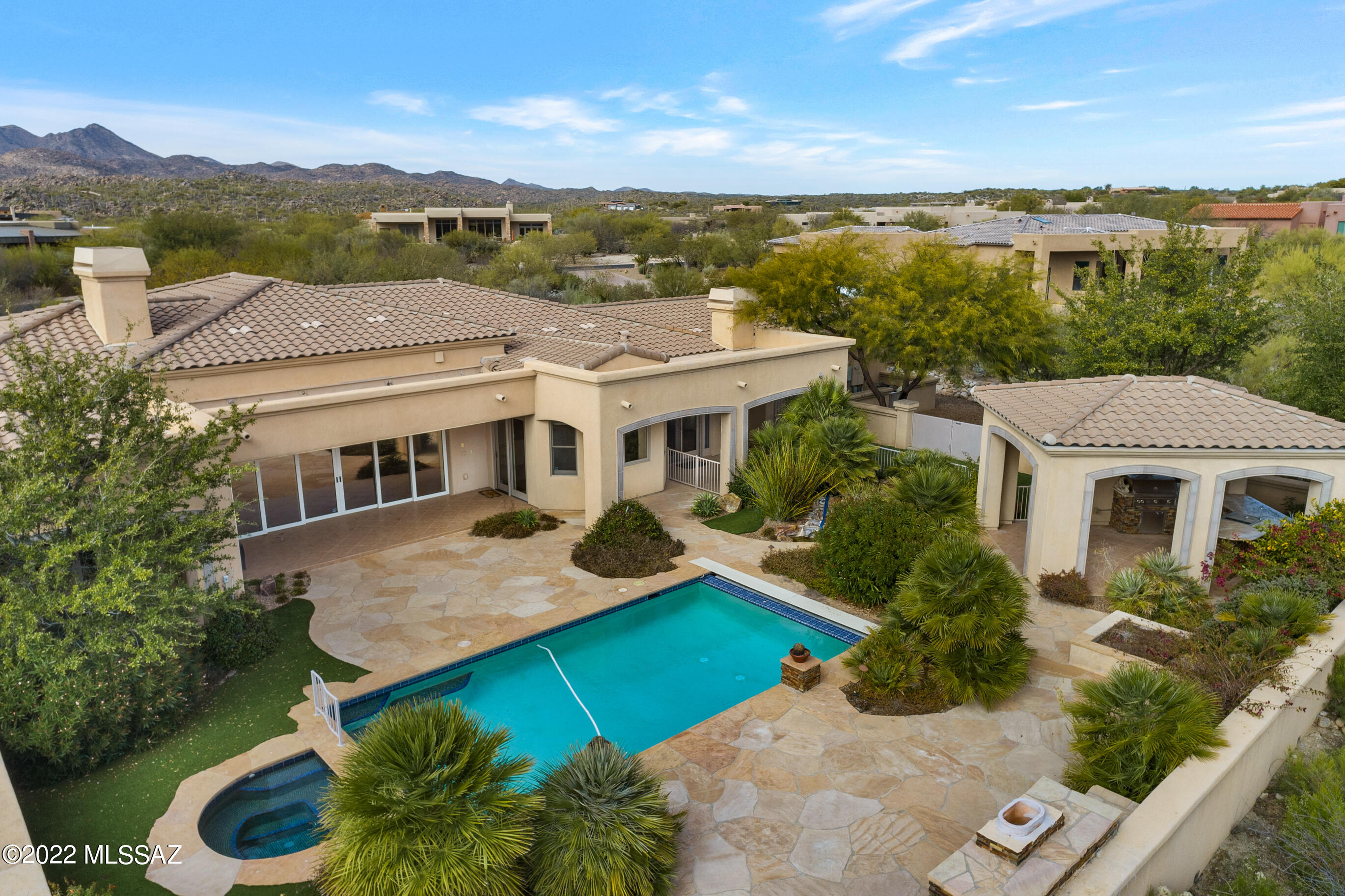 Enjoy your own private oasis and FABULOUS VIEWS of Pusch Ridge from this beautiful 5 bedroom/4 bath home in desirable guard-gated Honey Bee Ridge within the Rancho Vistoso Community of Oro Valley. Fantastic floor plan boasts several private patios, 2 large living areas, 2 fireplaces, plus 1 by the pool, and plenty of storage and space for everyone. Enjoy indoor/outdoor entertaining with expansive sliding glass doors in the living room leading to the pool, spa, and outdoor kitchen. A special dog run is a feature off the garage, plus an artificial turf side yard. Kitchen features a Sub-Zero refrigerator, and Jenn-Air double ovens.  Home sits far off the street on 1 acre, with over 4,300 square feet and a 3 car garage, plus a spacious concrete aggregate driveway. Don't miss!