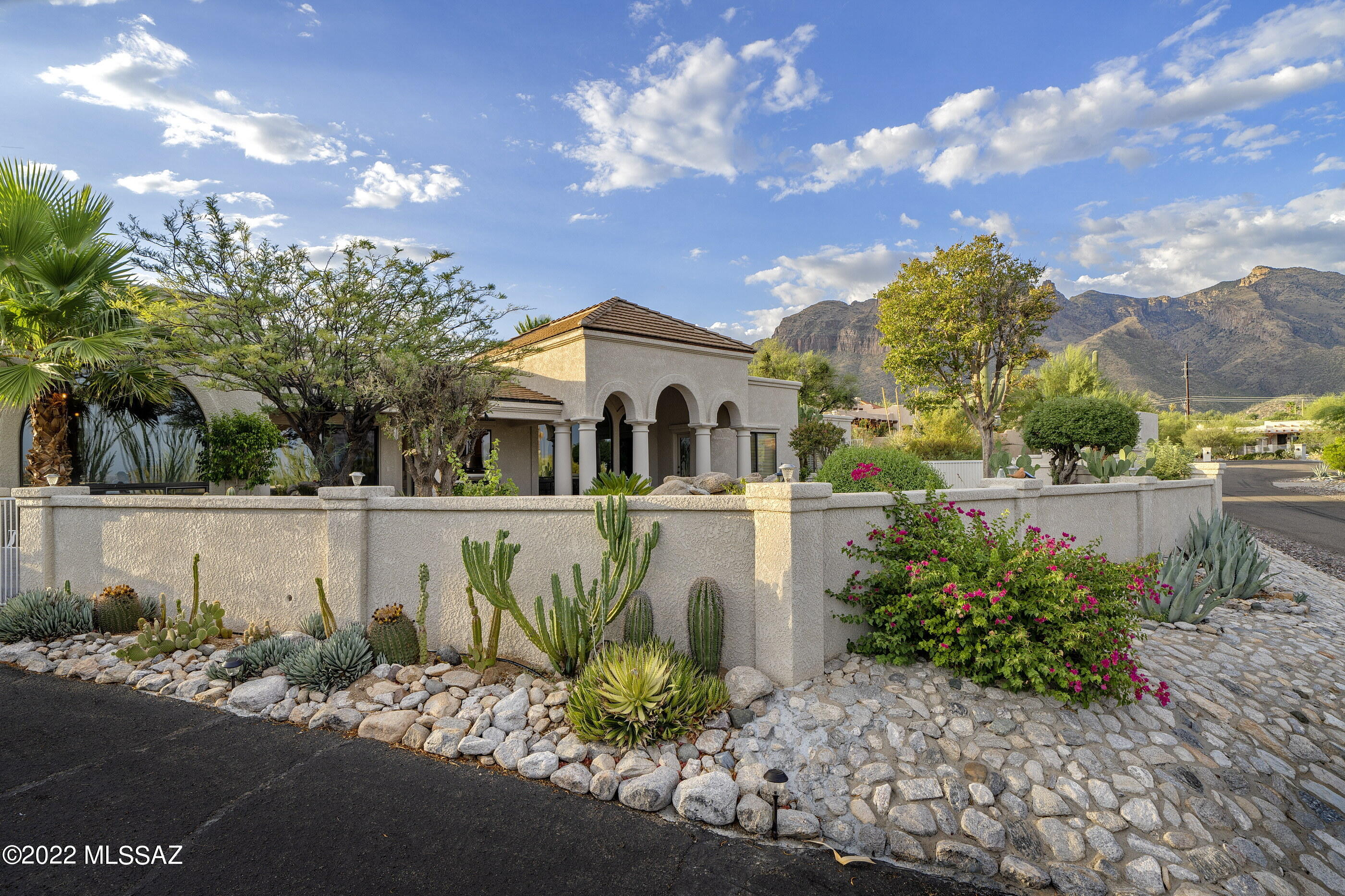 Custom Foothills home on private cul-de-sac with beautiful city and mountain views close to La Encantada, Manzanita Elementary, and Campbell Trailhead. This split floor plan home has 5 bedrooms and 3 full bathrooms and is open and bright with plenty of natural light. The high ceilings are complimented by arched windows and doorways that provide a resort-like feel. The kitchen features a dining area and is spacious with granite countertops, large granite island, walk-in pantry, and plenty of cabinets. Well-appointed master suite features a sitting area with cozy fireplace and access to the backyard, a dressing area with spacious dual closets, and the bathroom dual vanities, jacuzzi tub, and separate shower..... The interior also features a butler's pantry with additional storage, separate formal dining and living rooms, stone tile flooring throughout, and plantation shutters on most windows. Tasteful updates have been made to the bathrooms and lighting fixtures throughout the home. The backyard features well-manicured landscaping, pool, pond with stream, and large fireplace. The covered brick paver patio is extensive and perfect for entertaining guests throughout the seasons while overlooking Tucson to the south and the Catalina Mountains to the north.