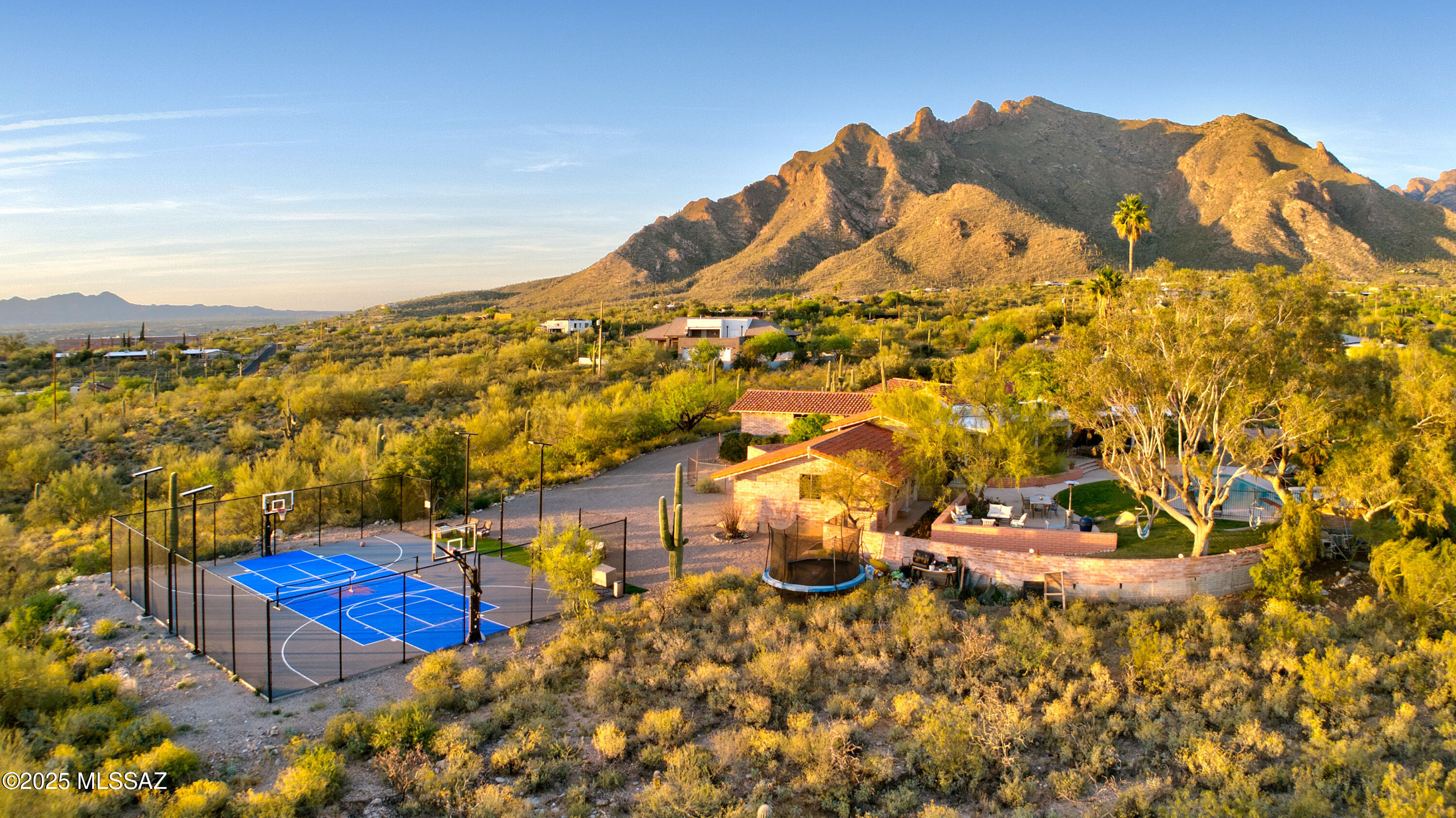 Nestled on 4.56 acres in Cobo Catalina Hills within the sought-after Catalina Foothills, this stunning ''classic Tucson'' home is truly one-of-a-kind. Rumored—though unconfirmed—to be designed by renowned Tucson architect Anne Rysdale, the 4,304 sq. ft. residence exudes meticulous craftsmanship and attention to detail.
With 4 spacious bedrooms and 7 elegant baths, this architecturally significant home offers a perfect blend of rustic charm and modern convenience. Enjoy sweeping mountain and city views, including the dramatic Pusch Ridge, from walls of glass that frame the picturesque landscape. The home's unique character is highlighted by burnt adobe construction with chrysocolla stone accents, a brand-new mission tile roof with chinked mortar and underlayment, and soaring beamed ceilings.
Step inside through hand-carved wooden doors into an inviting foyer adorned with marble-tiled flooring. The spacious living room, featuring a cathedral tongue-and-groove ceiling, offers breathtaking mountain vistas, while the comfortable family roomwith its high beamed ceiling and stone fireplaceflows effortlessly into an expansive, heated and cooled Arizona room, perfect for entertaining or a game room for pool and ping pong.
The remodeled kitchen is a chef's dream, boasting Bianco Romano granite countertops, travertine flooring, and top-of-the-line appliances including a Wolf warming drawer, two Sub-Zero refrigerated drawers, a Sub-Zero refrigerator, a Wolf gas cooktop with double ovens, a wine fridge, and Hallmark maple cabinetry.
 The gracious primary suite boasts an attached den/office.
Outdoor living is equally impressive. Relax by the large pool/spa with its soothing waterfall, enjoy the scenic views from multiple outdoor living spaces, or freshen up in one of the two outdoor bathrooms or the outdoor shower. A recently built solar-lighted sports court offers a versatile space for tennis, pickleball, or basketball. Additional updates include new xeriscape landscaping, drip irrigation, a whole-house water filtration system, new carpet, and numerous electrical and plumbing enhancements.
Experience the perfect harmony of timeless design and modern luxury in this remarkable Tucson estate.