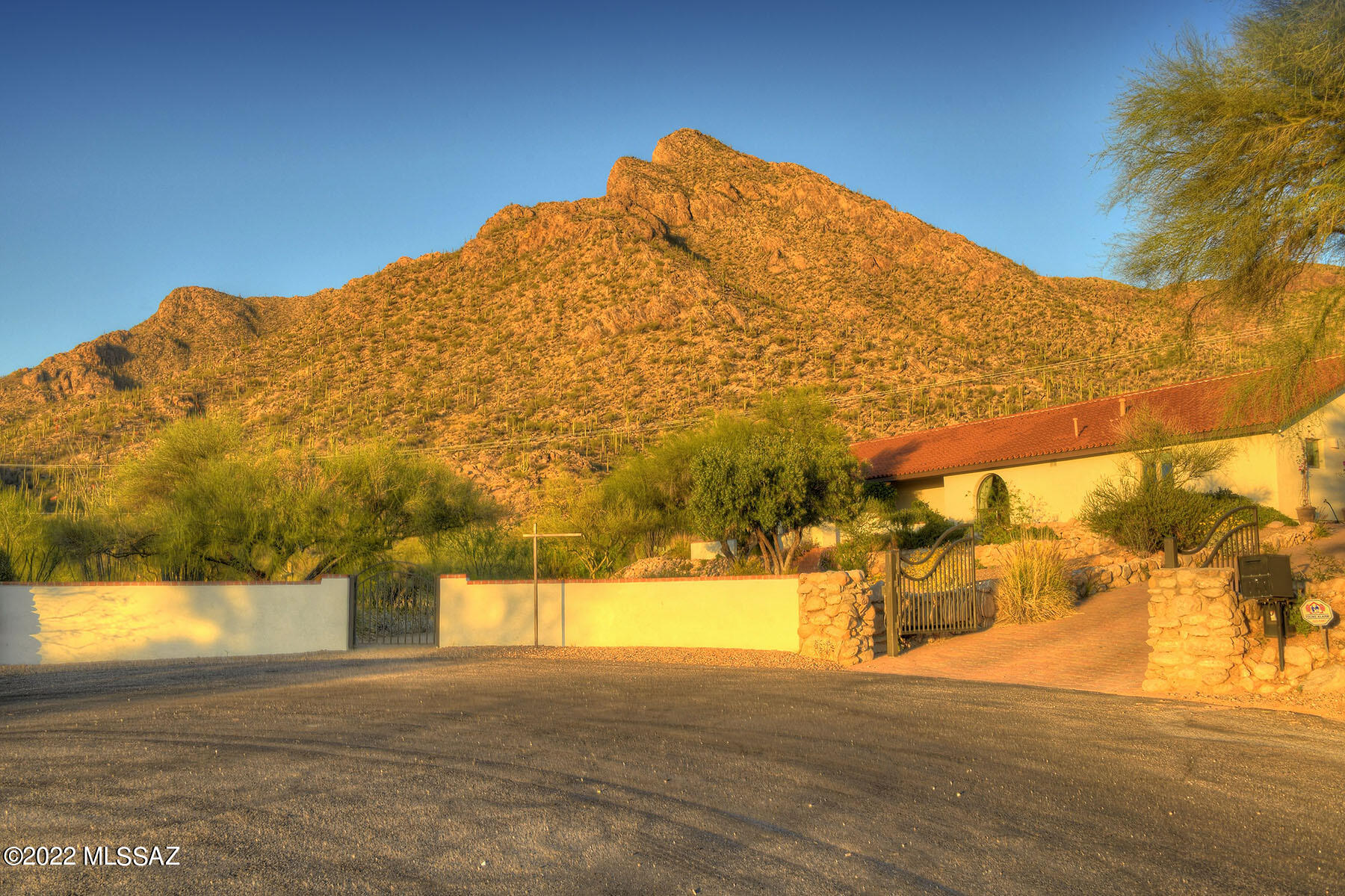 Spectacular Views of the Coronado National Forest and Pusch Ridge! Glorious and inspiring sunsets from your front porch! A rare opportunity to experience the vibrant beauty of the Sonoran Desert from your doorstep. Nestled at the base of Pusch Ridge and bordering the National Forest, privately gated and professionally landscaped on 1+ acre, this California Mission style hacienda expresses charm, character, and sense of place. The 2630 sqft home includes 3 bedrooms, 3 baths, split plan with spacious rooms, tile floors, decorative beamed ceilings, 2 beehive fireplaces and handsome built-in bookcases. 3 expansive walled and wrought iron patios expand outside living enjoyment. Property line extends beyond walled patios.  2 car garage. Owner/Agent
