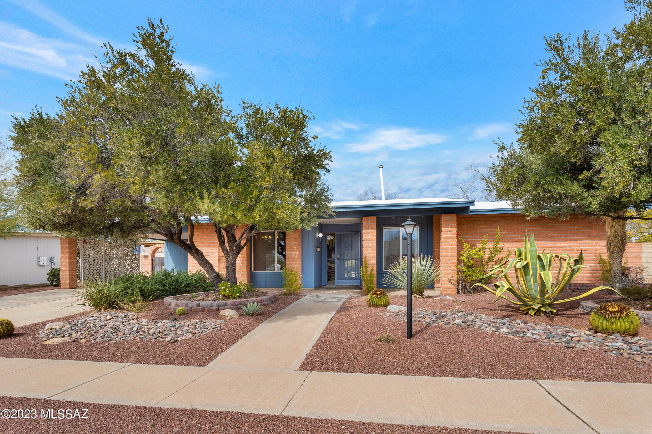 Nestled in Metropolitan Estates in NW Tucson, this ranch-style floor plan was designed as a 4 br/2ba. The original owners had it built as a 3/2 giving the extra area to the primary bedroom, creating a spacious suite with 2 large closets (one walk-in). The entire home has ceramic tile flooring set on the diagonal surrounded by 4'' baseboards. Granite counters were added to the bathrooms and kitchen. There is a 10'x50' north-facing covered patio with a lovely sense of privacy. A three-tiered fountain is encircled by 1,100 sq ft of pavers and is the focal point of the walled rear yard along with the local hummingbird population. In 2022, the railroad ties in the yard were replaced with a beautiful exposed-edge block retaining wall. Other features include recent exterior paint & 'See more' roof coating, auto irrigation for front/rear yards, skylights and solar tubes, large laundry with extra shelving, large storage room/workshop. No HOA!
