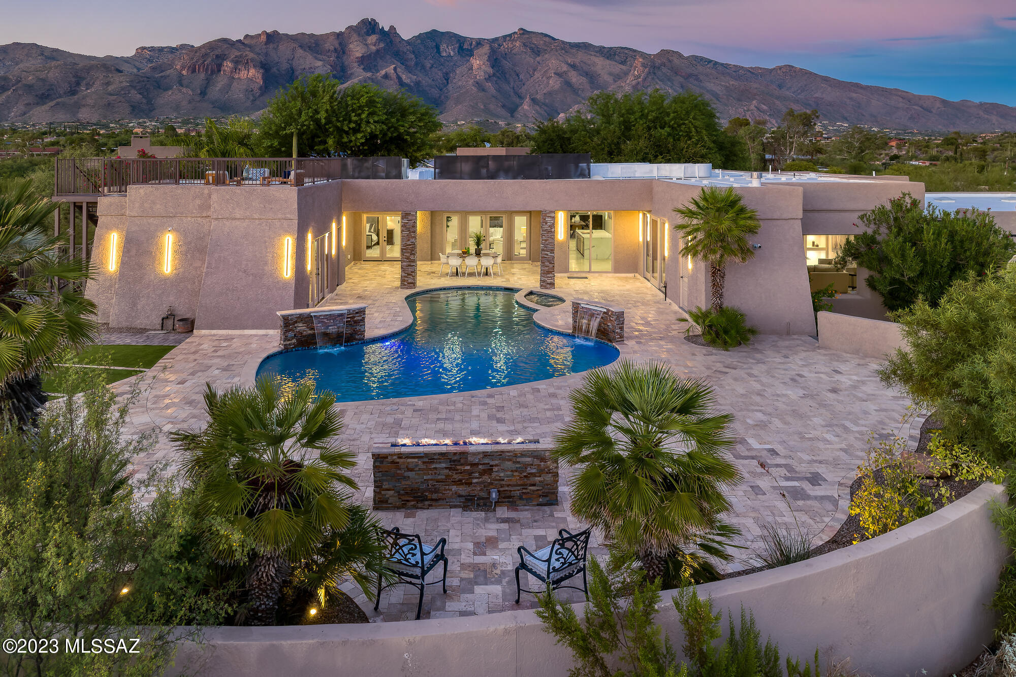 TOTALLY REMODELED, LIKE-NEW, CONTEMPORARY estate in the heart of the Catalina Foothills - a painstaking 1½ year passionate gorgeous transformation of a classic masonry 1.21 acre homesite.  Bespoke luxury at all levels! Be the first to occupy it! This Sophisticated compound, known as ''The Campbell Estate,'' is nestled at the end of a private enclave of 7 custom homes and boasts 2 private automatic gates. The most discerning owner will marvel at the alluring and immaculate interior and exterior finishes of the 9,887 square feet under roof.  Massive new gourmet kitchen and 7 new bathrooms. A car-lovers dream, 6-car garage, 2 electric car jacks. The physician who owns this estate spared no expense inside or out as he had planned this home for his own large family. The well-planned redesign opened all the interior spaces to seamlessly flow with high ceilings and tall doors. Extraordinary paved entry courtyard and tranquil spillway fountain welcome you with mature flowering vegetation, twinkling city lights and mountains views leading you to the stunning 8' glass entry pivot door. Meander down your private trail behind the house to bird watch, sip your morning java in your sun-filled atrium, or invite your guests to your rooftop deck to awe them with jaw-dropping views. Windows were strategically placed to capture viewpoints. Luxurious Gourmet Kitchen with 10' oversized quartz double-waterfall eat-at island, Custom created knotty alder cabinetry, appointed with high-end appliances including 2 dishwashers, 2 electric ovens, 2 sinks, 2 refrigerators, full wine fridge, 6-burner gas cooktop, full-size butler's pantry with desk area. All 6 bedrooms are ensuite with walk-in closets plus a powder room. The primary retreat has its own fireplace, a sitting area, a private office with a floor-to-ceiling window, French doors to a private inner courtyard and to the pool/spa. The primary bath with elegant floor-to-ceiling window behind the soaking tub captures the private desert beauty, double showers with rain showers and handhelds. The flex guest quarters with minikitchen can be used as a spa/exercise space. The outside pool/spa oasis has extensive travertine pavers, full high-end outdoor kitchen, generous turf area, and fountains. Meticulously redesigned for the most discerning homeowner with designer finishes and all NEW travertine floors and wide-plank wood floors in the living room, 3 new HVAC systems, new plumbing and gas lines, newly resurfaced pool/spa, new 8' doors, all new kitchen, all 7 bathrooms are new, new light fixtures, new drywall/insulation/paint, new roof, CCTV cameras, high-tech phone-operated gates and appliances, etc. County Permitted and inspected. Ideally situated between Tucson's finest shopping and dining centers, La Encantada and St. Phillip's Plaza, minutes to golf, UA, downtown, hiking. Sought-after District 16 schools.