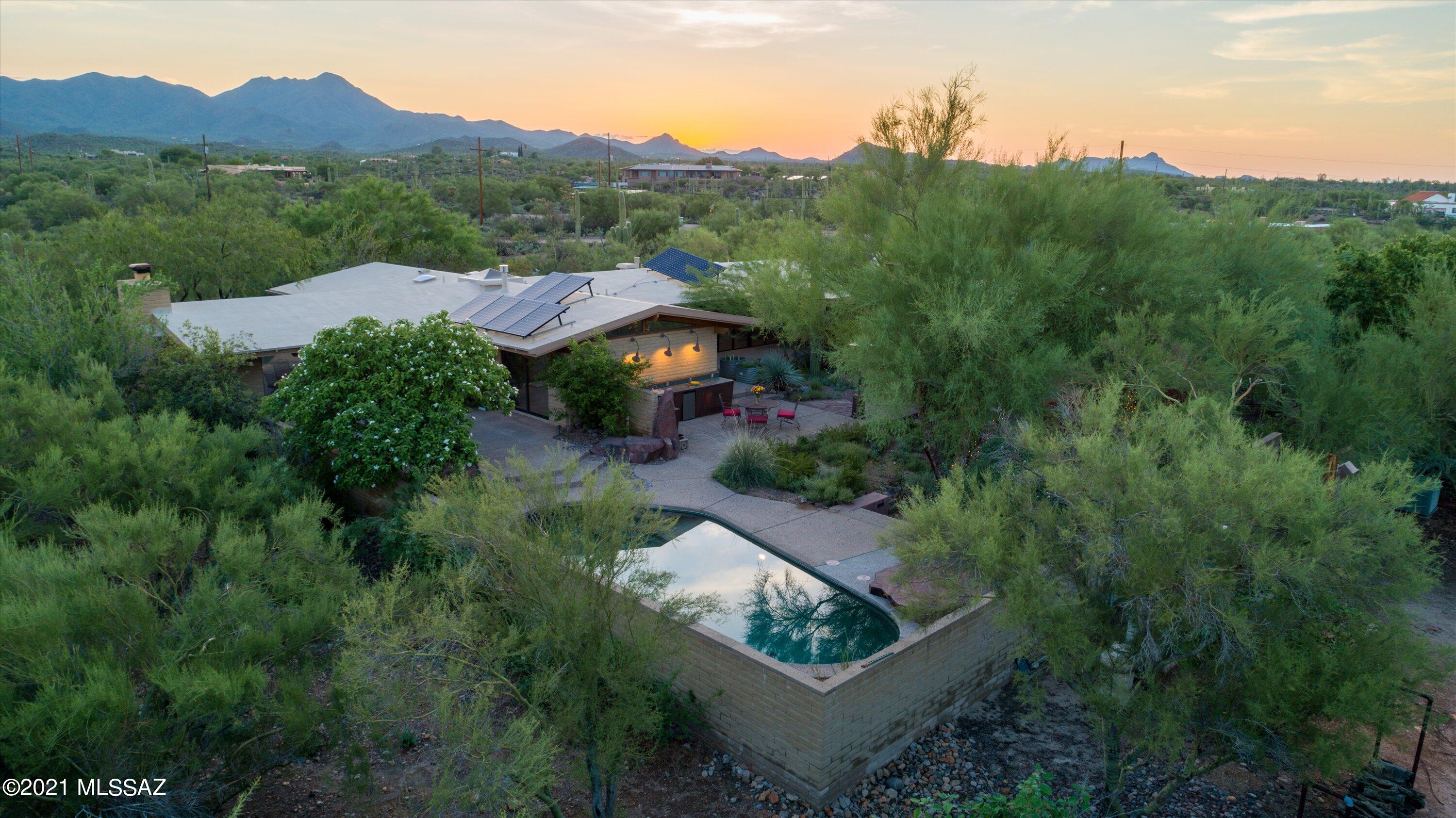 Unique, bright and tranquil home, ideal for outdoor living, entertainment & work from home.  Quiet neighborhood, wildlife & nearby walking trails.  Outdoor kitchen, gas grill, 5 unique patios., outdoor spa & pool, solar energy, water harvesting & 5000 gal cistern, enclosed custom drip irrigated fruit tree/vegetable garden.  Vaulted tongue/groove beam ceilings, skylights, clerestory windows, rock wall fireplace, wood floor, built-in bookcases.  Kitchen has stainless appliances, ample cabinets & pantry,. Master bath with 2 sinks, jetted bath & steam shower, exceptional storage space throughout house/garage.  Monitored alarm system.  Extra room (exercise) with its own mini-split AC/heat.  Additional detached custom designed studio/guest house with full bath, kitchenette, large closet, wood & stone floor.