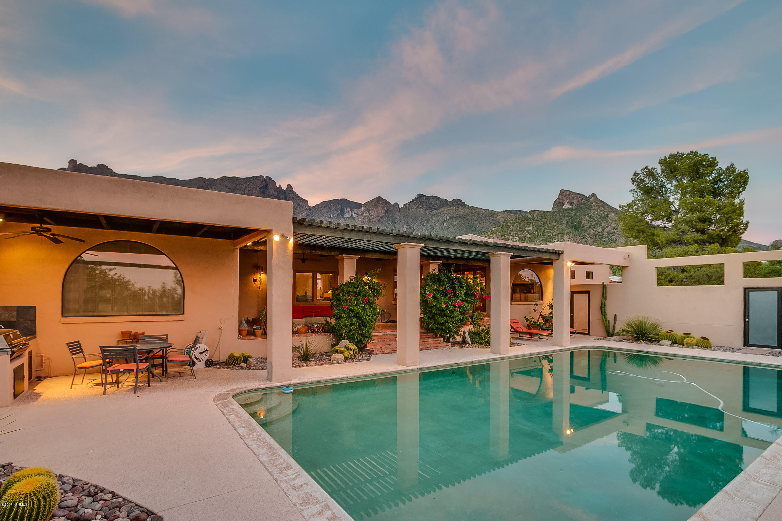 This architecturally unique home has awe-inspiring city and mountain views. Entrance is through the private gated courtyard and sculpture garden. The main 3BR home has a den, library, entertainment room, 700 bottle wine cellar & 2 fireplaces. Master bath has a steam and outdoor shower. Finger Rock views from the tranquil patio & recycling stream, resonant of Sabino Canyon. The GH has north facing windows, perfect for family, friends or an art studio. There is a 20 x 40 pool, secluded spa area with separate outdoor shower, and built-in BBQ off of the covered patio. Walk south of pool from the driveway and through the gate to the Tohono Chul-like meditation cactus garden. Minutes to Finger Rock trail, convenient to La Encantada, hiking, and the University of Arizona. District 16