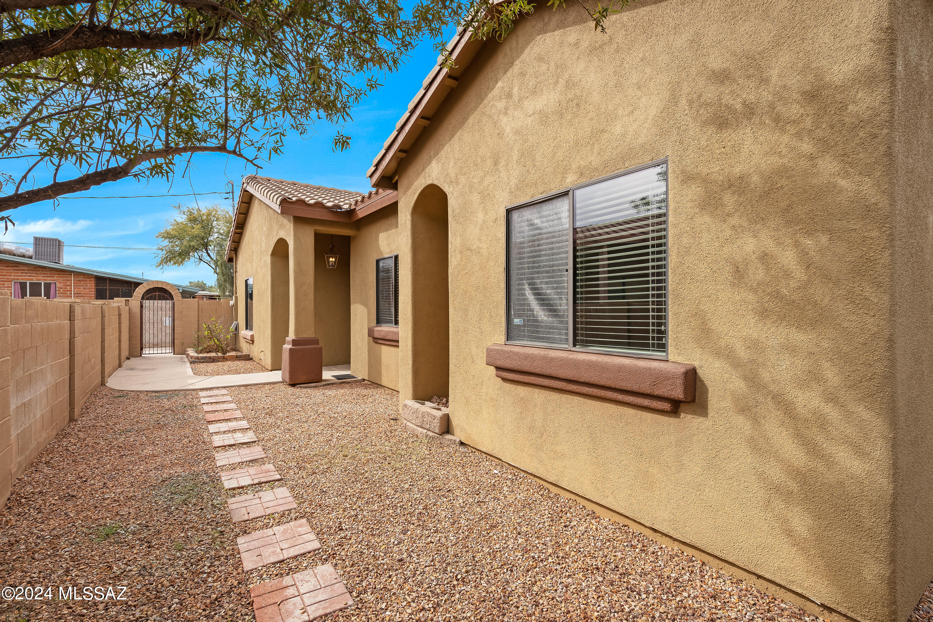 Privately sited off Tyndall St, this southwest contemporary features high, vaulted ceilings, open kitchen with stainless steel appliances, travertine countertops, handsome scored concrete floors throughout (no carpet!). Vaulted ceilings let in plenty of natural light. Primary bedroom has built in entertainment niches, walk in closet with ample shelving. Split bedroom floor plan, and neutral palette. 2 car garage! Backyard features covered patio, pavers, putting green, and both yards are very low care with natural desert plantings. A convenient central location, close to the UA, Mountain Ave bike path, and the Loop!