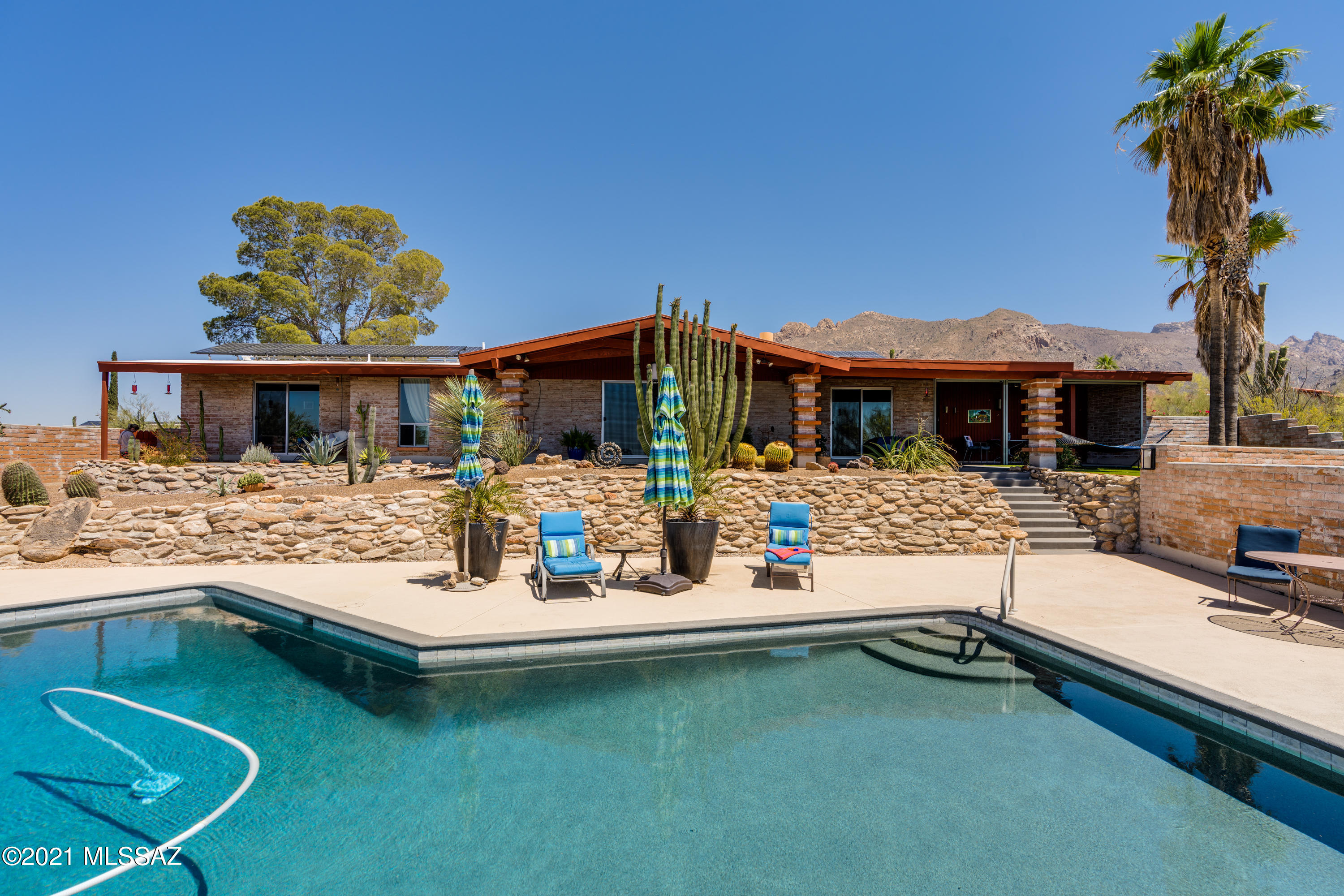 Beautiful burnt adobe mid-century ranch home w/spectacular city&mountain views.  A multitude of recent improvements have brought this home well into the 21st century, & it is turn-key/move-in ready.  With a well-designed 4BR, 2BA floorplan, the home includes a 2-car garage w/electrical outlet for E-car charging, remodeled kitchen, & master bath, owned solar (2020), 16-SEER HVAC (2018), double pane/low E windows installed throughout, new interior doors, rolling shades on west windows & a Catio w/its own incredible views. Long covered patio overlooks beautiful pool recently converted to saltwater w/updates including StoneScapes Mini Pebble interior, resurfaced pool deck & much more (see list of improvements). Incredible city&mountain views from everywhere, on this large, saguaro studded lot. A true birders paradise.  Enjoy the natural desert vegetation and wildlife and lots of hiking options.  All centrally located in the central Catalina Foothills with easy access to restaurants, shopping, schools, and the University.