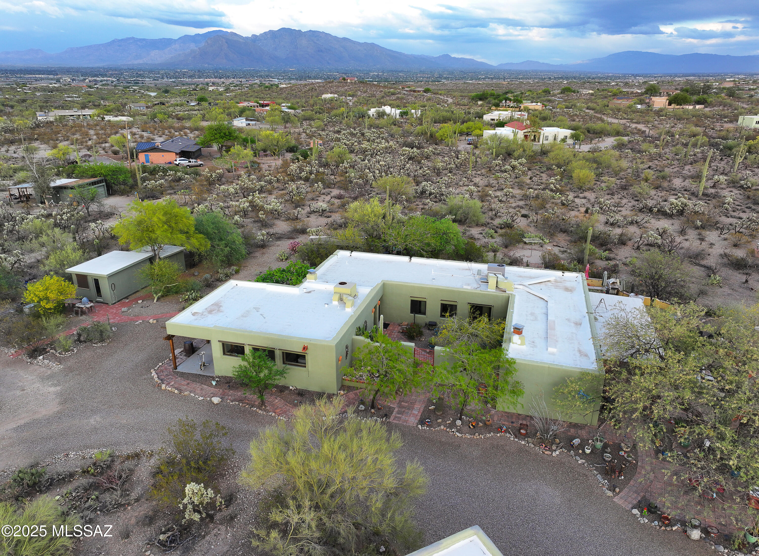 Charming mud adobe home with stunning desert views and 1,200 sq.ft. detached 3-car garage. Nestled on a spacious 3.3-acre lot with breathtaking mountain vistas, this authentic adobe home blends classic Southwestern charm with thoughtful updates. Exposed wood beams, tongue-and-groove ceilings and gorgeous brick floors highlight the warm and inviting interior. Open-concept living and dining area features a kiva-style fireplace, built-in entertainment center. Large picture windows fill the space with natural light. The kitchen boasts custom cabinetry, a newer stainless-steel bluetooth refrigerator and dishwasher, as well as Southwestern touches like hand-painted tile accents. Step outside to enjoy multiple patios, a serene courtyard, peaceful desert landscaping and meandering walking paths.