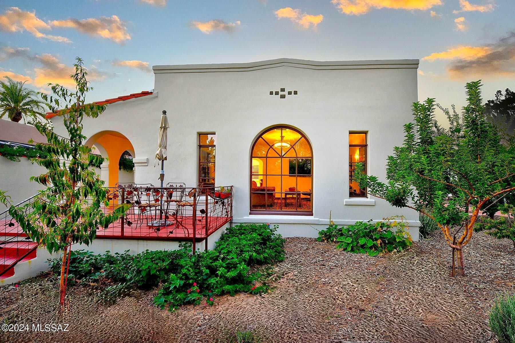 Welcome to a timeless masterpiece of Spanish Territorial Revival, meticulously crafted and built in Sam Hughes in 1933 and its original splendor. This elegant home greets you with a stunning entry porch adorned with graceful archways and original scored concrete, setting the tone for the charm that lies within. The historic residence boasts restored steel casement windows, now retrofitted with dual pane thermal glass inserts, which complement the coved ceilings and the beautifully preserved tiled fireplace with original working gas fireplace insert, authentic art deco light fixtures, and pristine white oak floors. These classic elements blend seamlessly with modern updates, creating a residence that is both historically rich and refreshingly contemporary. Step into the expansive living room and dining area, designed to host both intimate gatherings and grand celebrations. The updated kitchen, a chef's delight, features Caesarstone countertops, a stylish tiled backsplash, shaker cabinetry, stainless steel appliances, and a convenient breakfast bar. The open layout ensures that this space remains the heart of the home, seamlessly connecting to the large dining area. A generous utility and laundry room extends from the kitchen to provide a huge pantry, coat closet, and a bank of custom storage cabinetry.
This home offers three generously sized bedrooms, each with ample storage and walk-in closets. The primary bedroom, a true retreat, features a walk-in closet with built-in dressers, abundant storage, and an ensuite bathroom complete with a soaking tub, double vanity, and direct access to the stunning 1/3-acre walled yard. Here you will find lush gardens and a thriving orchard, including peach, pear, apple, pomegranate, cherry, jujube, mulberry, fig, orange, lemon, lime, grapefruit, and tangerine trees, automated drip irrigation, a sophisticated water harvesting system with a 865 gallon tank, alongside charming patios surrounded by specimen trees and flowering vines. The second primary bedroom includes an ensuite bathroom and a private entrance, making it an ideal space for guests or a home office. The third bedroom also enjoys access to a dedicated bathroom.
The property further boasts modern conveniences such as smart home technology and a replumbed, insulated, and updated infrastructure, and an amazing amount of storage space. The two-car garage has been expanded, providing ample off-street parking, while electronic gates and custom wrought iron details enhance security and style. Enjoy unparalleled access to Himmel Park just steps from your back gate and take advantage of the proximity to the University of Arizona, views of the Catalina Mountains, local restaurants, and other amenities. This residence offers not just a home, but a lifestyle, one of elegance, convenience, and vibrant community living.