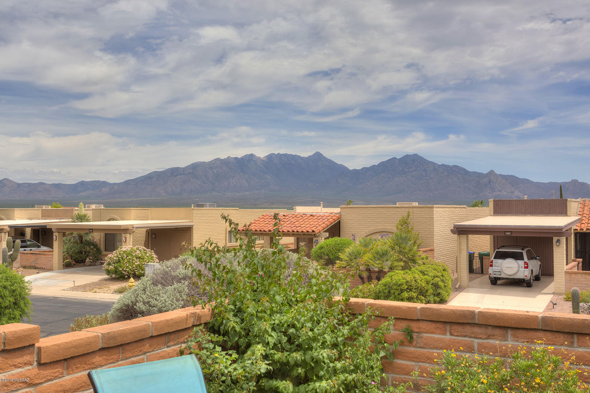 Enjoy the fantastic mountain views from the back patio of this end-unit townhouse in Desert Hills.  This home features wood-look ceramic tile through out, extra custom cabinetry in the kitchen, newer counter tops and solid surface sink. The living room and master bedroom are extended adding lots of extra living space. The retractable awning on the back of the home provides a little extra shade when you need it and awnings on the east facing windows keep the home cool in the morning.  The garage door on the carport gives you  privacy and the front sitting area has a patio cover and draw-down sun shades. This is a desert jewel you don't want to miss! Some furniture available on SBOS.