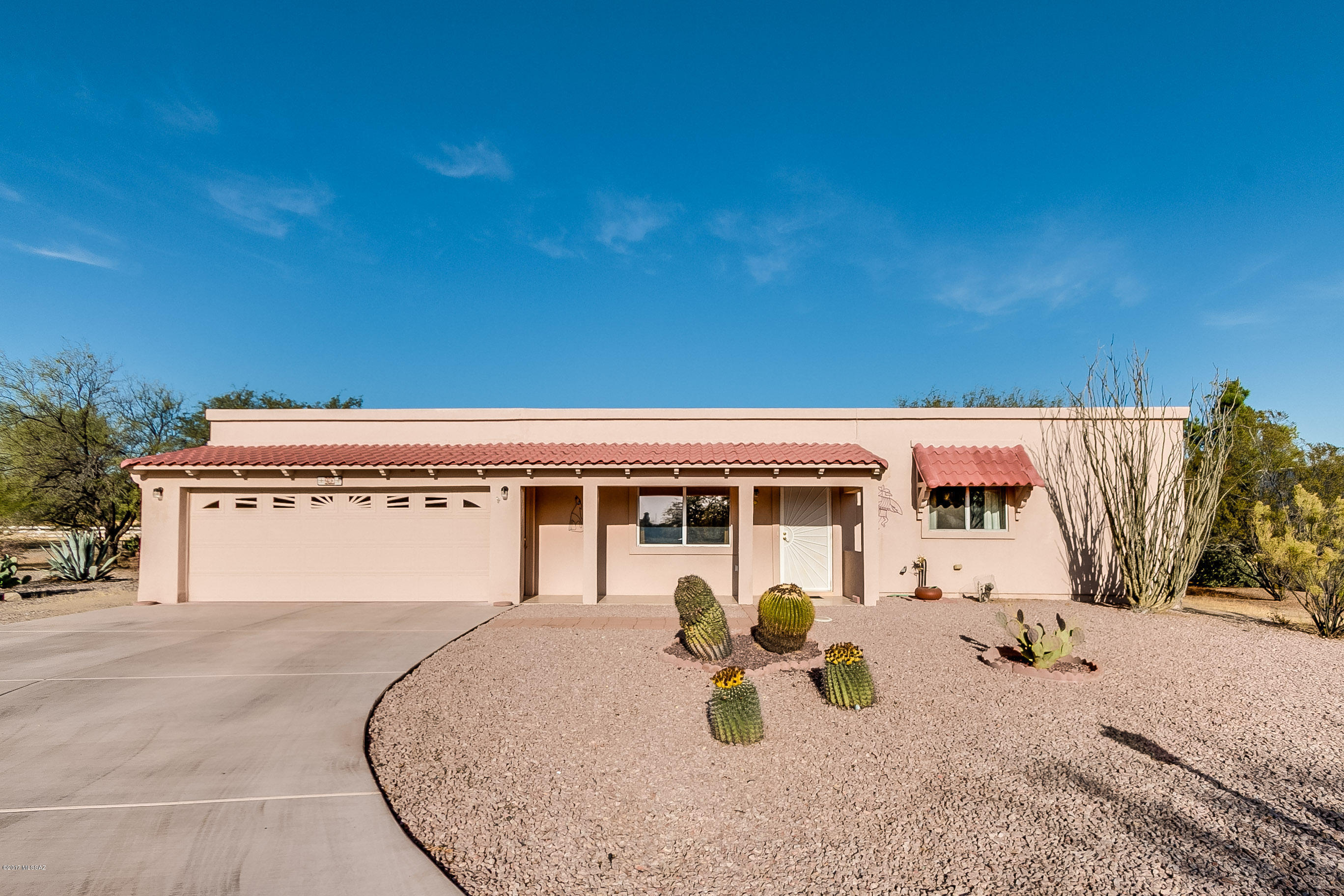 This home has a traditional look with Spanish tile roof over a charming front porch with views of the Santa Rita Mountains. You’ll enter a conventional living room with large picture windows, tile flooring and arched passageways. Warm wood laminate flooring flows through the dining area into a classic kitchen offering a convenient pass-through window for easy delivery of snacks to the back patio or just around the corner to the family room with fireplace. The wood flooring continues into the master suite with walk in closet and master bath displaying colorful custom tile accents. The guest bedroom also has its own bath with custom tile shower. Looking for more storage space? Wait till you see the garage with its natural light beaming through decorative windows, multiple ceiling storage racks, a built-in workstation, generous cabinetry and coated floor treatment. Set on a lot designed for getting away from it all, you'll love the shady back patio where you can enjoy the refreshing feeling of an expansive low maintenance lot enclosed within a red block perimeter wall adjacent to open space and natural desert.