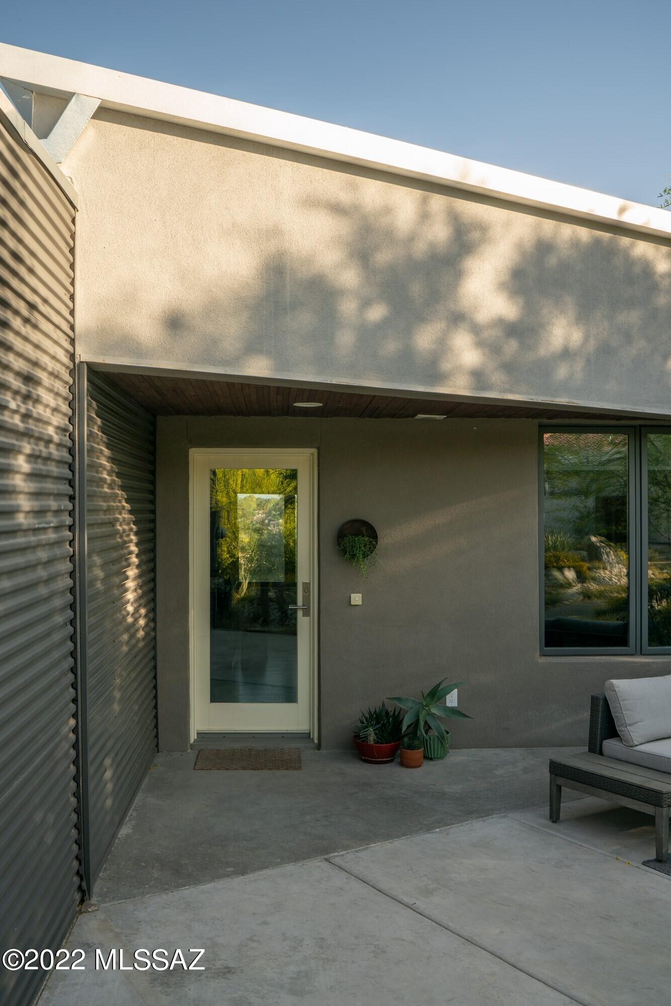 Find sanctuary in this Architect designed modern home on the hillside.  Designed by Architect Bil Taylor and completed in 2012 this 2 story home takes its cues and shape with a hillside design that follows the topography and minimizes its impact on the site. Thoughtful in orientation and experience, it has been skillfully sited to capture the panoramic views of the city while providing utmost privacy. One enters the home and is greeted by the open plan of public spaces – living, dining, kitchen, powder room and an office or flex space.  Open and airy, natural light floods the upper level throughout the day from all directions. Bamboo floors, energy efficient appliances and modern casework are found in the public spaces. Off the kitchen and dining area a glass door opens to a covered patio  an ideal setting for watching the monsoons roll in or enjoying the sunset fade into illuminated city lights.
The open stair takes one down to the private spaces.  A generously sized main suite consisting of bedroom, large bath, walk in closet and covered outdoor patio with an outdoor shower. The second bedroom is roomy with an ensuite bathroom. laundry room is situated conveniently between the 2 downstairs bathrooms. 
The property has been designed with efficiency in mind  siting, orientation, views, all electric, triple pane windows, water filtration system, 3 cisterns, solar water heater and native plantings.  The home has also been prepped for solar should new owner want to install. A separate 2 car garage and workshop space greets you at the property line, separating the car and allowing for a walk thru the gardens as you enter the home.   Located off the River bike bath, with direct access for early morning rides or a mid-day walk.  Minutes to exceptional shopping and restaurants.