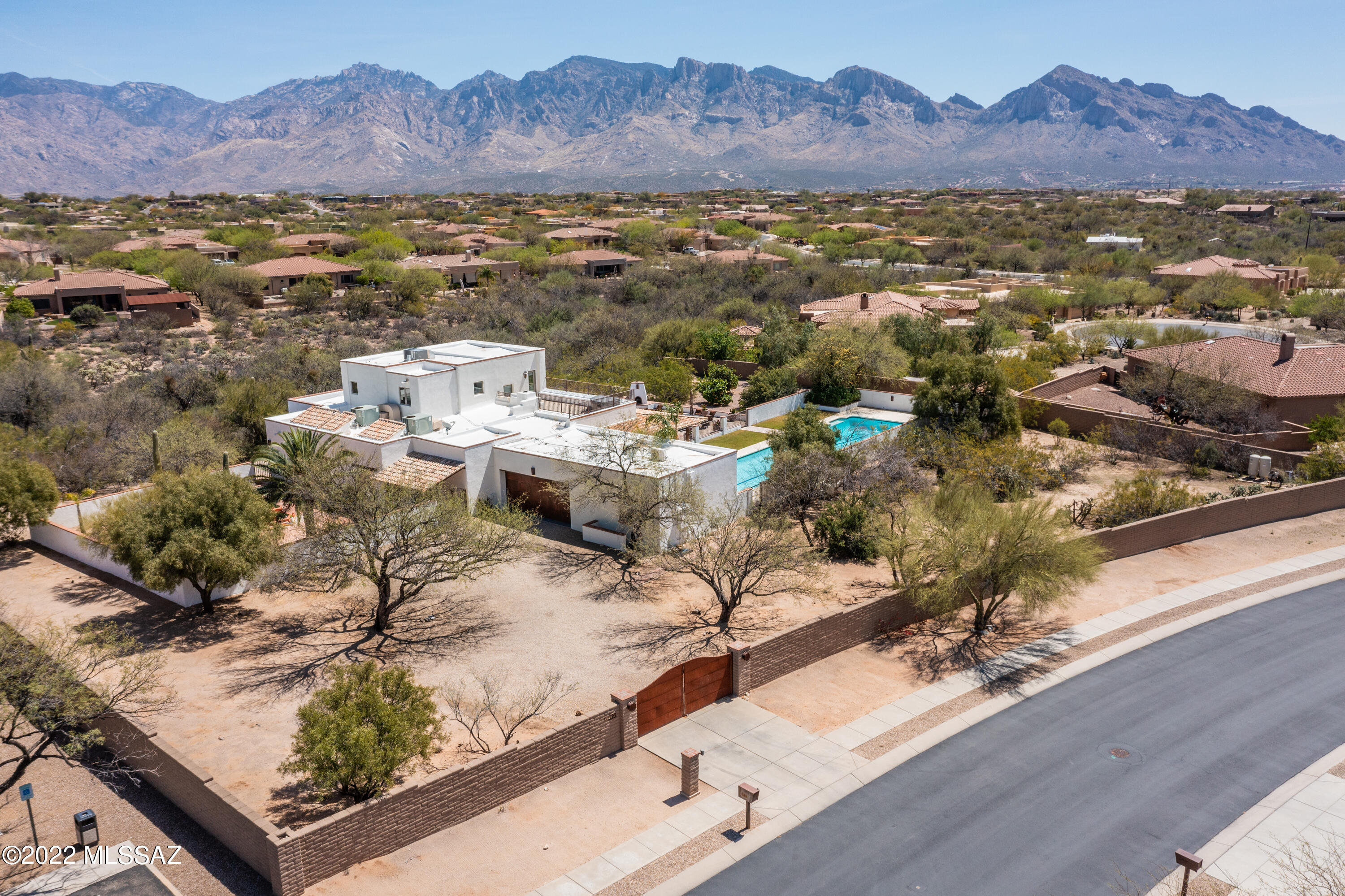 Exquisite Spanish-inspired adobe home situated on large 1.28 acre lot with endless views!  This is a MUST SEE.  Enter through the private gate to a fully enclosed yard and private courtyard.  Brick floors throughout the downstairs, adobe white walls, oversized windows, wood burning fireplace and more.  Primary bedroom is upstairs with breathtaking views of the Catalinas, large walk-in closet, and private balcony with it's very own hot tub.  Enjoy Tucson outdoor living with built-in BBQ and kitchen, outdoor fireplace, extra large lap pool, and two covered patios and citrus trees.  Off the garage there is a bonus room perfect for home gym, office or guest room. And, the home features its own private well.  Located next to the community park. This home has it all!!!