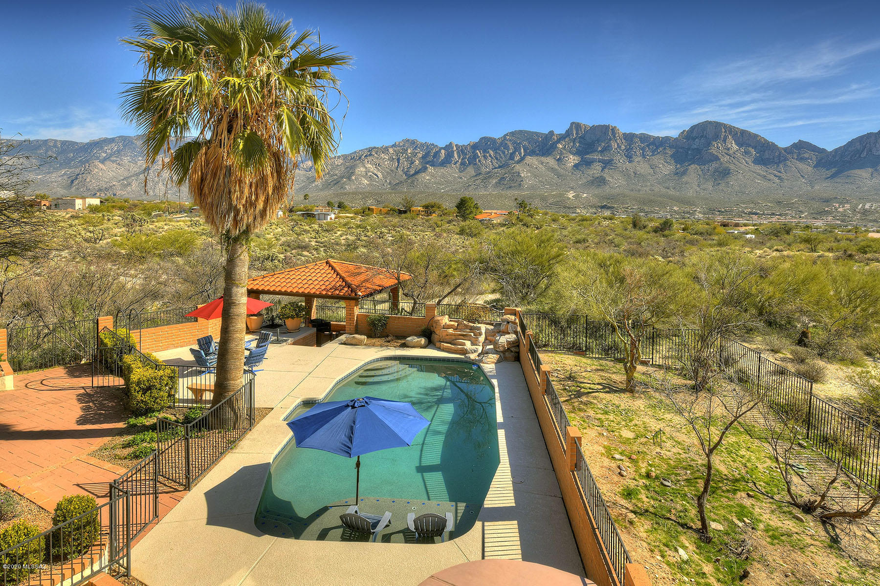 Custom home on 3.35 acre lot with panoramic, unobstructed mountain views, located in the heart of Oro Valley! Solid Masonry construction with Beamed Ceilings in the Great Room, Master Bedroom and Patios! Five bedrooms, four bathrooms split plan plus a basement recreation room. Upgraded kitchen boasts custom solid wood cabinetry, soapstone counters and wine bar. Resort style living with luxurious lagoon-like pool & waterfall overlooking pristine desert and mountains. Enjoy the pink mountains at sunset & nighttime stargazing from the hot tub or roof top viewing deck. Backyard ramada is perfect for entertaining. Horse property with no HOA!   Three car garage includes three storage rooms.   Room for a guest house and additional out-buildings.  Remarkable and Rare, don't miss this gem!