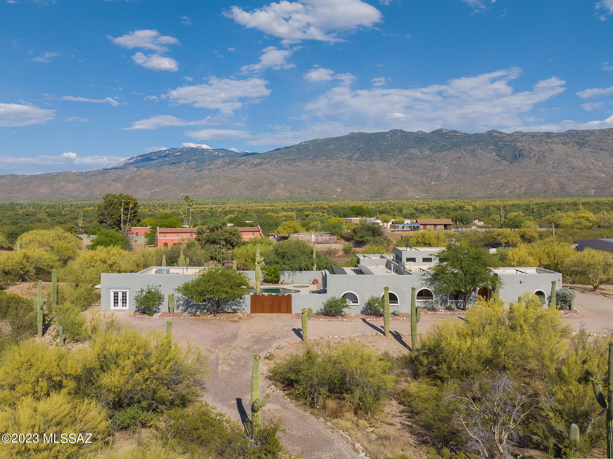 This 4+ acre horse property is just a short ride to the Sahuara National Park East. Sweeping views and abundant Saguaro cactus make this property a tranquil retreat. A spacious open kitchen with quartz countertops and stainless appliances opens the great room with vaulted ceilings and kiva fireplace. The main house offers a split plan with three bedrooms, each with its own en-suite bathroom. Additional spaces include a den, arizona room, and office (or gym) area in Primary suite. Primary bath has large walk-in shower, separate tub, private toilet, dual vanities, and an adjacent half bathroom with pool access. Beyond the pebble finish pool and spa is a large guest house with one bedroom, kitchenette, and bonus room which would make a great art/hobby studio or bunk room. Metal horse paddock, large grazing area, chicken coop, and shed make this an ideal starter ranch or multi-generational homestead.