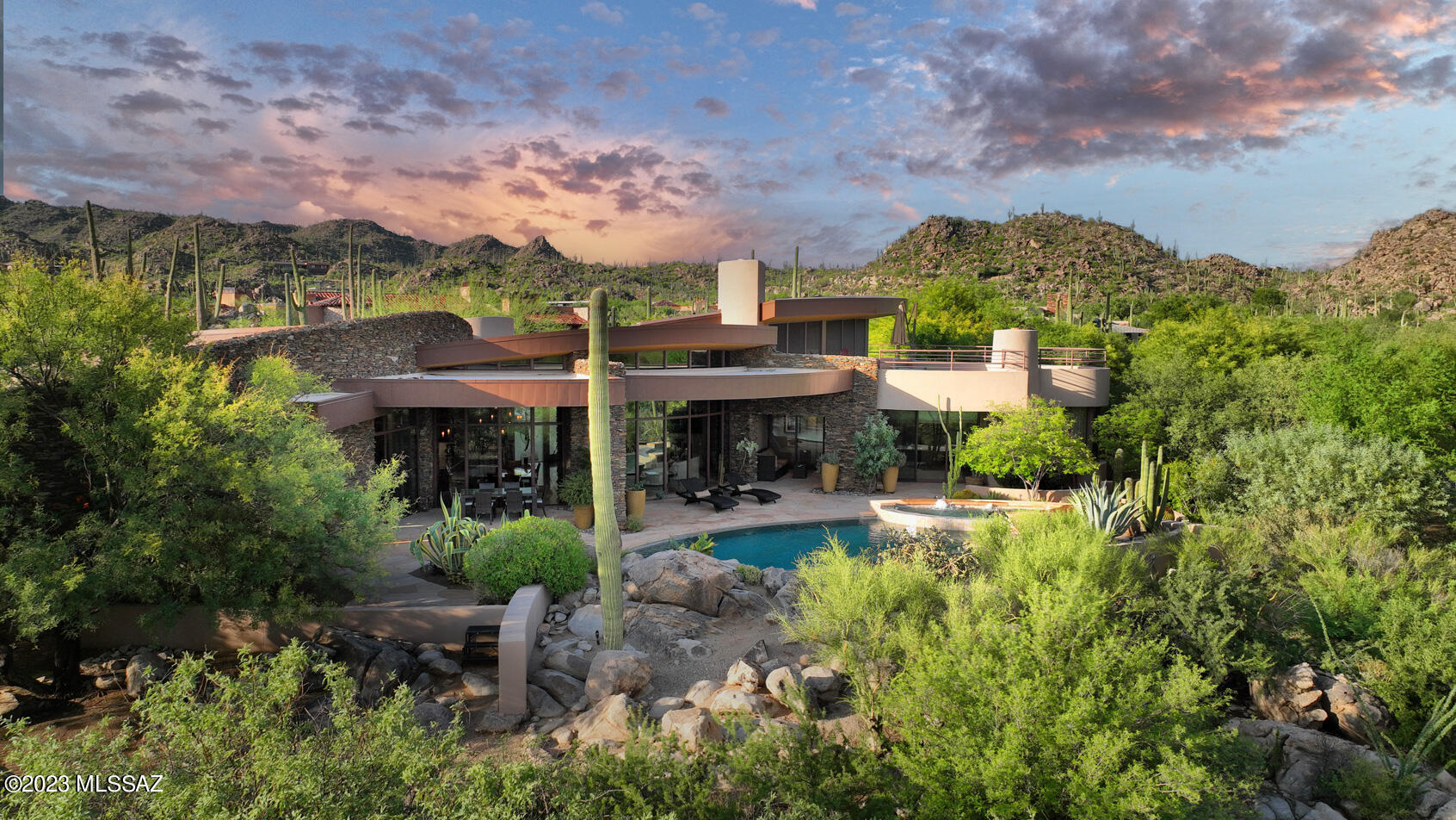 Located on the 11th green of the Stone Canyon Club, this dramatic and timeless contemporary, designed and built by award winning architect Kevin Howard, is a true work of art.  Situated on a private lot with extensive views of the Catalina Mountains and Pusch Ridge as well as golf course and city lights especially from the wonderful loft and roof top retreat. You will find incredible architecture, attention to detail, and high end finishes in every aspect of this 4,885 sq ft, three bedroom/four bath home... starting with the circular motor court leading to the dramatic etched glass entry, custom stacked stone walls, custom 8' solid wood doors with metal inlays throughout the home, polished limestone flooring, luxury lighting fixtures, abundant natural light from massive floor to ceiling windows, motorized blinds, custom built-ins, wet bar with wine and beverage storage, flagstone patio, enchanting pool with spa and waterfall, outdoor kitchen, and misting system.  Your guests will love the private 542 sq ft attached guest house (included in the overall 4885 sq ft).  Significant improvements in 2020 include a newly remodeled kitchen and master bath, all new Wolf and SubZero appliances, new high efficiency HVAC systems, new Tesla back up battery for the owner-owned Solar system, new carpeting in bedrooms, and new variable speed high efficiency pool/spa pumps.  Come see for yourself why The Stone Canyon Club has become the most sought-after exclusive gated community in Tucson, featuring a Health and Fitness Center, Pool and Spa, World Class Golf Course, Clubhouse, Restaurant, and Amazing Lifestyle.
