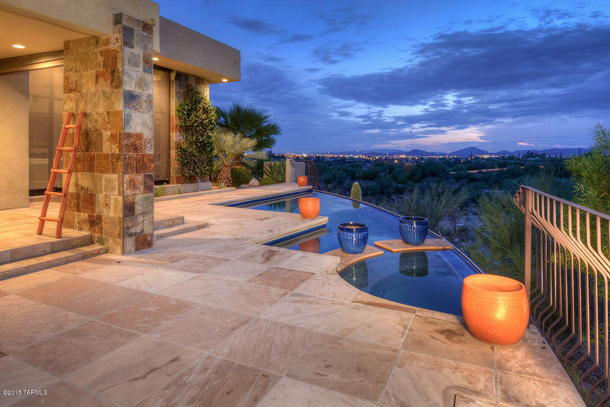 Outstanding soft contemporary on a private cul-de-sac lot in the Catalina Foothills with sweeping city, desert, sunset and Catalina Mountain views. Enter into living room with soaring ceilings, walls of windows, fireplace and travertine floors leading to gourmet kitchen with designer SS appliances, center island, granite counters and family room with fireplace. Gracious master suite offers sitting room and master bath with natural stone surrounds. Large laundry/work room, 3 car garage, professionally landscaped yards and flagstone walkways, covered porches with travertine floors, outdoor kitchen with kiva fireplace, bancos and negative edge pool and spa. Full golf membership to Ventana Canyon Country Club is included with the property.