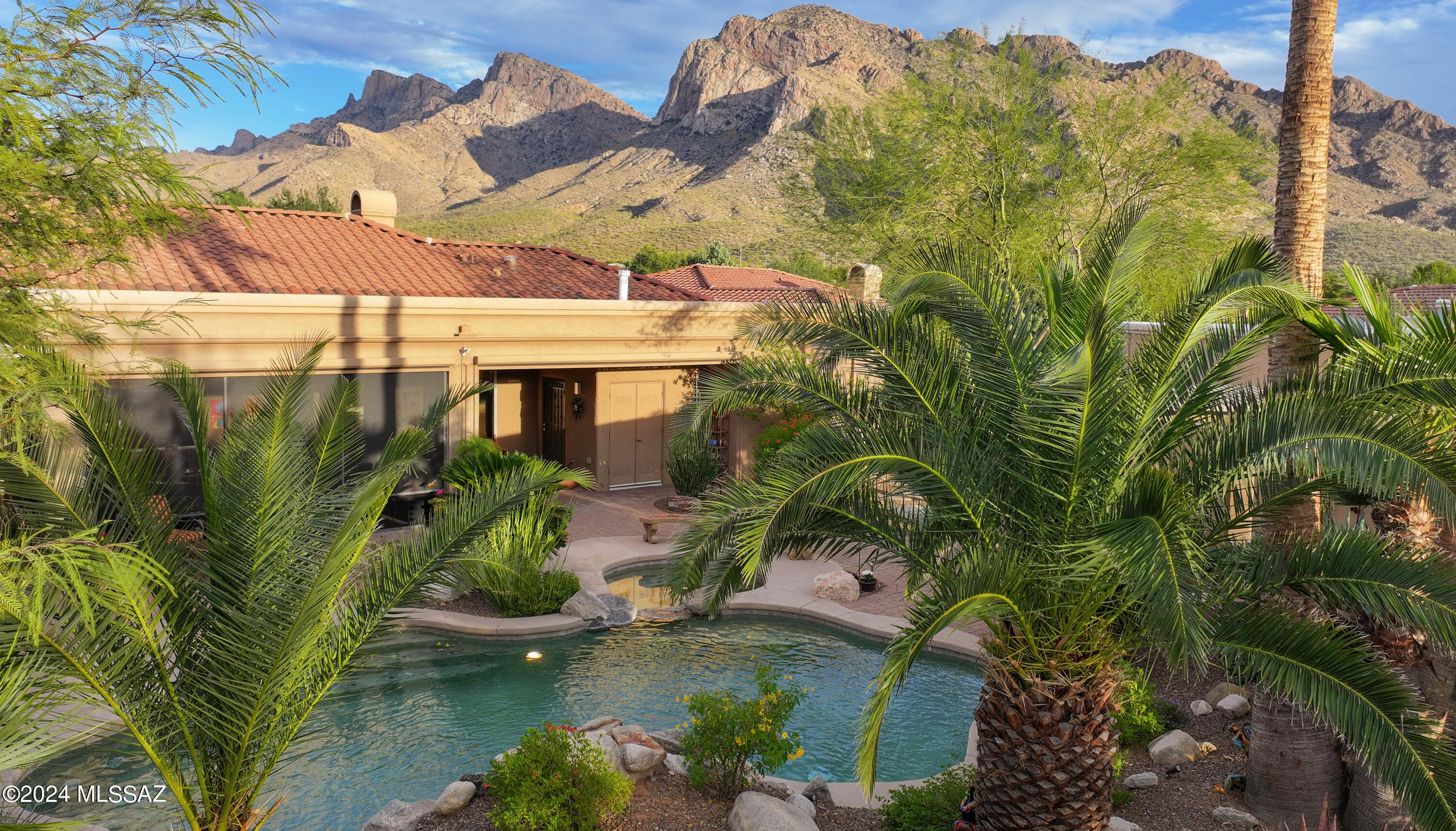 Nestled within the Oro Valley Country Club community and the gated Sunstone Estates, indulge in luxury living in this beautiful three-bedroom, three-bath residence on 0.3 acre lot. As you arrive, the brick paver front courtyard, framed by the majestic Catalina Mountains, warmly welcomes you into this exceptional property. This thoughtfully designed 2,896 SF home features a spacious Great Room adorned with a gas fireplace, custom built-in cabinets, and an entertainment center. The well-appointed kitchen boasts stainless steel appliances, including a microwave/convection oven, oven, warming drawer, 5-burner gas cooktop, island for meal preparation, and walk-in pantry for ample storage. The private primary suite offers a den with a built-in desk and custom cabinets; updated primary bath showcases a walk-in shower, executive height vanities, and private access to the backyard. The California Closets custom-designed walk-in closet is sure to please.  Outdoor living is a delight with a sparkling pool and spa accompanied by a soothing waterfall. Entertain guests under the pergola on the outdoor patio and barbecue center. A screened-in patio provides a tranquil space to relish the outdoors. Additional amenities include a split floor plan, an oversized two-car garage with built-in cabinets and cooled storage, roof replacement (Oct 23), travertine floors, high ceilings, formal dining room, and water softener. As a finishing touch, savor stunning views of the Catalina Mountains. Don't miss the opportunity to claim this meticulously designed residence as your home, where you'll enjoy Arizona living at its finest.