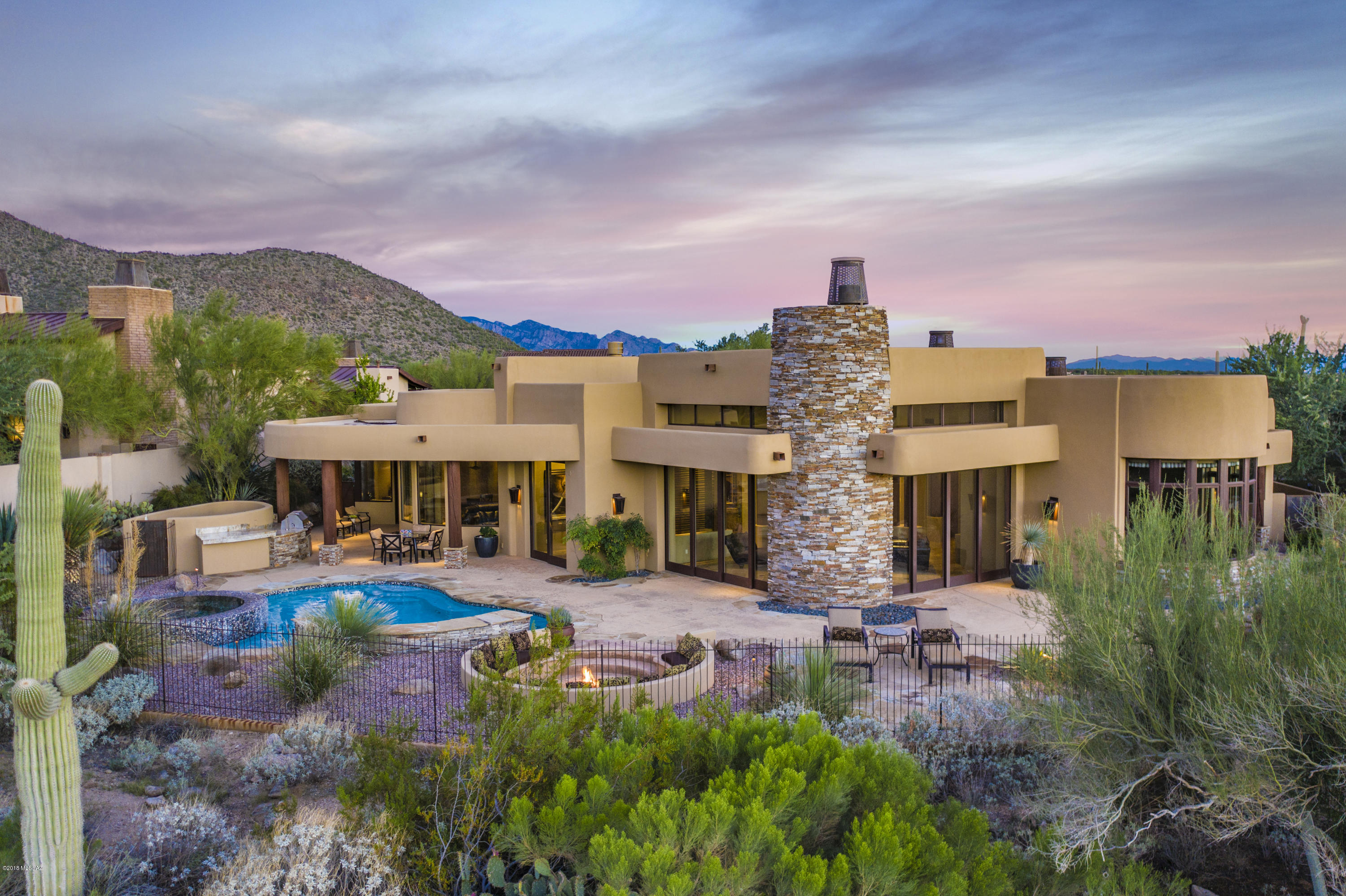 Former model at Gated Ritz-Carlton Residences at Dove Mountain in Tortolita Mountain foothills just minutes to downtown Tucson. Enjoy a lifestyle that is fascinating & delightful utilizing Ritz hotel & spa amenities, clubhouse, golf, Olympic-size pool, hiking, biking & walking trails.4,836sf 4BR/4½BA home + 574sf 1BR/1BA guest casita. Private courtyard w/water feature & fireplace. Impressive custom metal pivot entry door to great room w/soaring tongue & grove ceilings & fireplace strategically placed between two collapsing disappearing window walls. Natural stone/hardwood floors, granite counters, Sub Zero/Wolf appliances, home automation & wine room. Each BR is ensuite w/private bath. Pebble tec pool/spa, fire pit & outdoor kitchen w/golf course, mountain & sunset views. 3 car garage.
