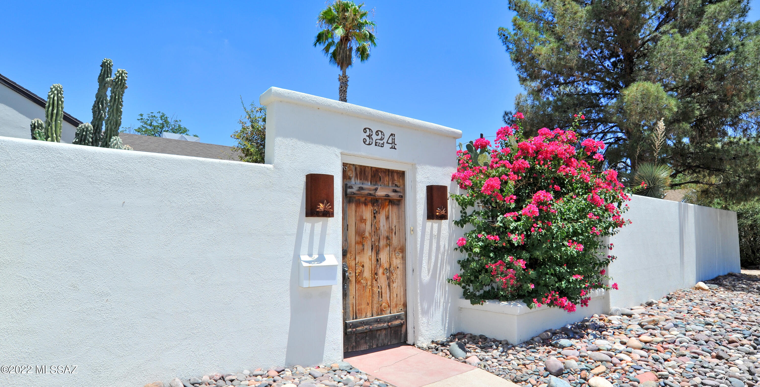 Classic Sam Hughes bungalow, perfectly located within walking distance of UA and the amenities surrounding it. The courtyard wall encircling the home creates a private sanctuary featuring mature trees, specimen cacti, numerous patios and entertaining areas and a sparkling swimming pool.  Updated kitchen and bathrooms feature warm neutral finishes. Large private primary suite with covered patio overlooks pool. Original charm intact with a deep front porch, fireplace, wood floors, original doors and hardware. Comfort and livability with upgraded windows, new tankless hot water, new ductless split in primary bedroom suite, new Bosch dishwasher, new HE stacked washer/dryer and recently lined sewer run. Abundant storage and parking with detached garage, two car carport and three storage sheds.