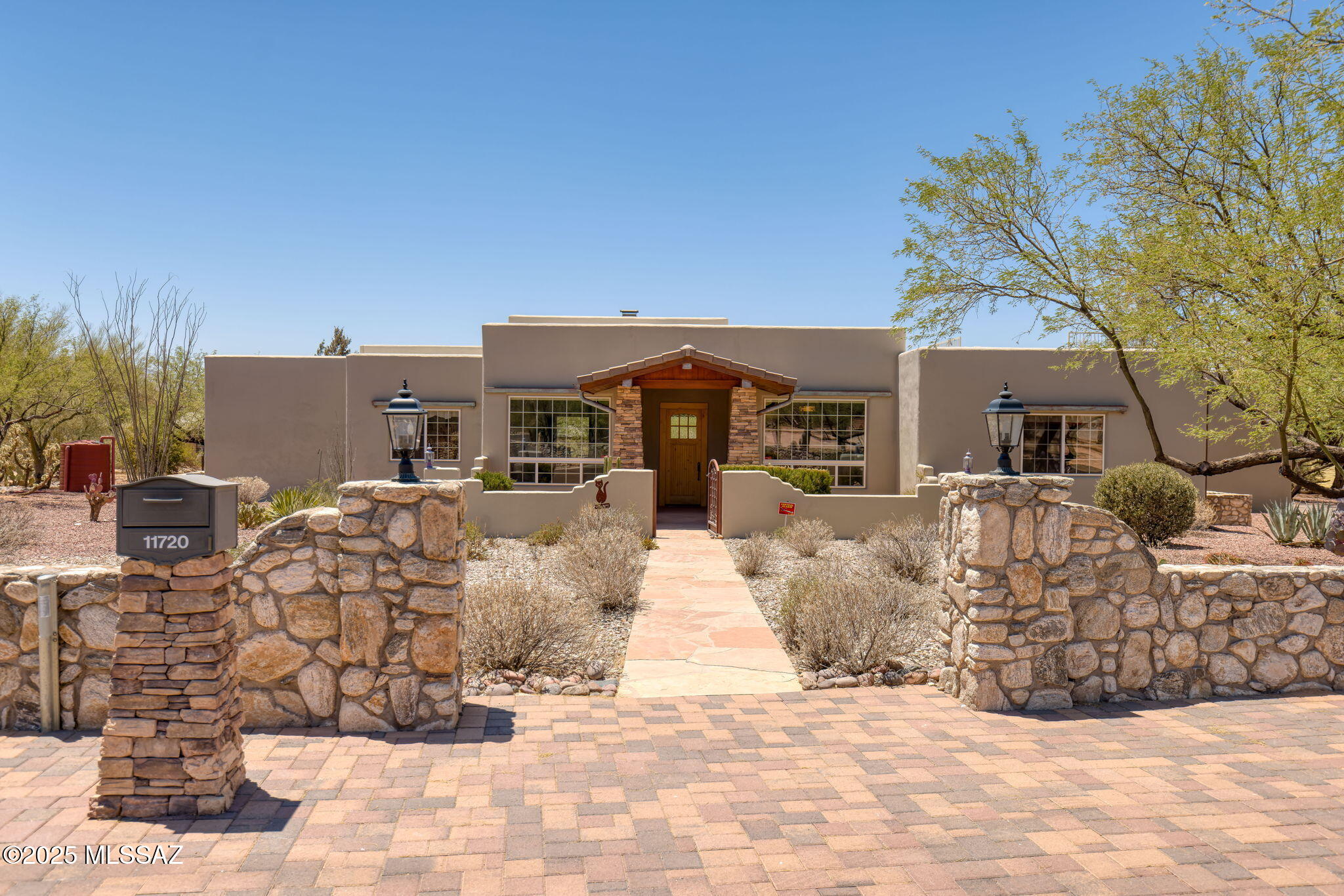 Santa Fe-style elegance meets modern comfort in this stunning custom home on over an acre in the desirable Tanque Verde Valley. Enjoy soaring wood-beamed ceilings, a spacious open layout, and dramatic mountain views from the gated front courtyard. The gourmet kitchen features granite countertops, custom cabinetry, and high-end appliances including a Viking wall oven and Thermador induction cooktop. The split floor plan includes a luxurious primary suite with spa-like bath and dream walk-in closet. Outside, a Pebble Tec pool, spa, and rooftop view deck offer desert living at its finest. Located in the acclaimed Tanque Verde School District, this beautifully maintained home is rich in detail: copper rain gutters, knotty alder doors, custom screen doors, and thoughtful touches throughout. The sitting and dining rooms feature automated shades that reveal the beautiful Catalina Mountain views. The main living/family room includes raised hearth stone fireplace, perfect for entertaining or cozy evenings. Split bedroom plan with all bedrooms featuring engineered hardwood floors; Bedroom 4 includes a built-in desk  with views, and Bedroom 2 closer to the primary suite is ideal for a nursery or craft room due to the built-in ironing board. Step outside to a flagstone covered patio overlooking lush mature desert landscaping, a sparkling Pebble Tec pool and spa, and custom rainwater harvesting system. A staircase leads to a rooftop deck with panoramic views of the mountains and city lights and nature of the Sonoran Desert. Dual-zone HVAC (2020), Nest thermostats, Roof coated May 2025,  central vacuum system, water softener system, 3-car side-entry garage,  and extensive built-in storage complete the package. Minutes from Agua Caliente Park, AZ National Golf Course, Mt. Lemmon, hiking, and shopping. This home is the perfect desert retreat and a must see! Now priced below recent appraisal of $875K. Call your favorite Realtor for a tour today.