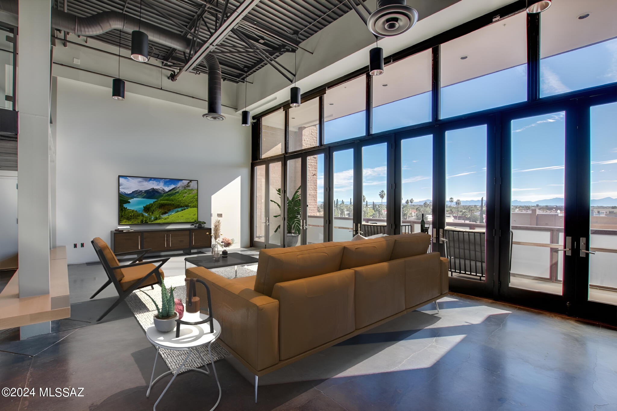Don't miss this rare opportunity to own a loft that combines modern design, functionality,
and breathtaking views! Step into a world of contemporary sophistication in this distinctive loft condominium perched high above downtown Tucson. The residence is adorned with magnificent floor-to-ceiling windows that fill the space with natural light, creating an inviting and open atmosphere. The loft's open layout creates a seamless flow from the gourmet kitchen to the spacious living area. Modern design meets functionality, providing an ideal space for both entertaining and everyday living. The kitchen is a masterpiece of culinary craftsmanship, featuring rift-sawn white oak cabinetry throughout, state-of-the-art appliances, ample counter space, and a stylish breakfast bar. This thoughtfully designed space is perfect for culinary enthusiasts who appreciate both form and function. Polished concrete floors throughout the loft add a touch of refinement, contributing to the sleek, modern aesthetic. The atmosphere is further elevated by open truss double-height ceilings, creating a sense of grandeur and expansiveness. This architectural feature not only enhances the visual appeal but also adds to the overall uniqueness of the space. Immerse yourself in the inventive use of space, highlighted by a distinctive mezzanine levelan architectural element introducing an additional layer of character and versatility to the loft. Step outside onto your expansive 30-foot private balcony and be captivated by unobstructed views of downtown, the Cathedral of St. Augustine, the Santa Rita Mountain Range, and majestic "A" Mountain. Whether enjoying your morning coffee or hosting an evening soiree, this outdoor space becomes an extension of your living area, offering a perfect blend of serenity and sophistication. The privileged positioning of this loft guarantees unparalleled privacy, enhanced by restricted elevator access that adds an extra layer of security. Furthermore, indulge in the convenience of an air-conditioned, secure 10x10 storage space, seamlessly integrating practicality into your living experience. Enjoy the convenience and peace of mind with private gated parking. This residence includes an assigned parking space within the building's garage, ensuring you can come and go with ease in the heart of downtown Tucson.