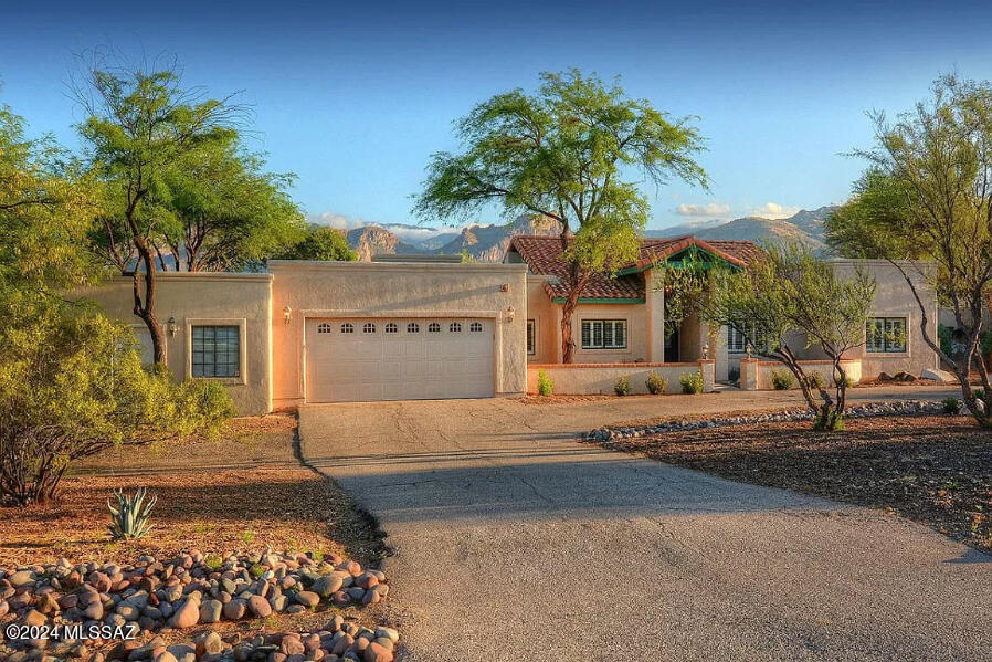 This meticulously maintained 3,587 sq. ft. Southwestern contemporary is nestled on a .90-acre lot and offers sweeping Catalina Mountain views. Located on a quiet cul-de-sac street this residence features 5 bedrooms, 3 baths, a 2-car garage, and a 3-room heated & cooled office with separate street entrance. Additional highlights include a circular driveway with zero-scape landscaping, a welcoming courtyard, a crystal encrusted Pella double entry door, a formal dining room, a spacious living room and a family room with a stacked stone two-way fireplace, skylights, and vaulted ceilings. The generous gourmet kitchen offers an oversized island with breakfast bar, granite counters, a separate desk, and a sink with reverse osmosis water filtration, plus a whole house water filtration system. The main living area offers porcelain tile flooring, the bedrooms come with bamboo flooring, and carpeting in the office. The gracious primary suite features a walk-in closet, a spa tub, dual sinks and a spacious shower. Additional features include a laundry room with a utility sink, ample storage throughout, 2 water heaters, 3 zones of HVAC, recently painted interior & exterior, and a newer roof (less than 2 years old). Recent upgrades to the home include electrical, plumbing, painting, the roof, and skylights. Enjoy the beautifully landscaped and walled-in back patio offering an expansive covered porch, a 9' deep swimming pool, a hot tub, a fountain, and panoramic mountain views. No through traffic on this quiet street, plus close to McDonald Park and walking trails. See to appreciate!