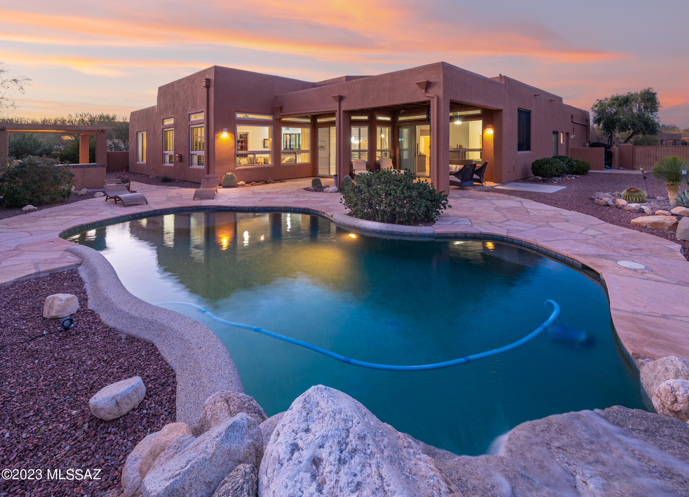 Situated in the highly sought-after Moonridge neighborhood, this beautiful home captivates you with an outdoor living oasis and unrivaled Pusch Ridge and Santa Catalina Mountain views. From the custom-designed front gate, through a charming courtyard to the massive mesquite front doors you are welcomed to a home filled with special touches. Skylights, large windows and high ceilings create bright, airy rooms. Solid fir doors open into comfy bedrooms, such as the spacious primary suite leading to the covered patio. Time will be well spent grilling under the ramada, unwinding, and hosting friends in the large backyard which boasts an oversized flagstone pool deck, a sprawling covered patio, pebble tec pool with natural waterfall feature, and desert landscaping to enhance the breathtaking views. Bring the entertainment back inside, in this open concept floorplan with ample granite countertop space in the kitchen and bar area. Make it a movie night in the dedicated media room or cozy up by the stacked stone fireplace with a good book. This home is sure to have a spot for everyone. Floorplan and virtual tour available upon request.
