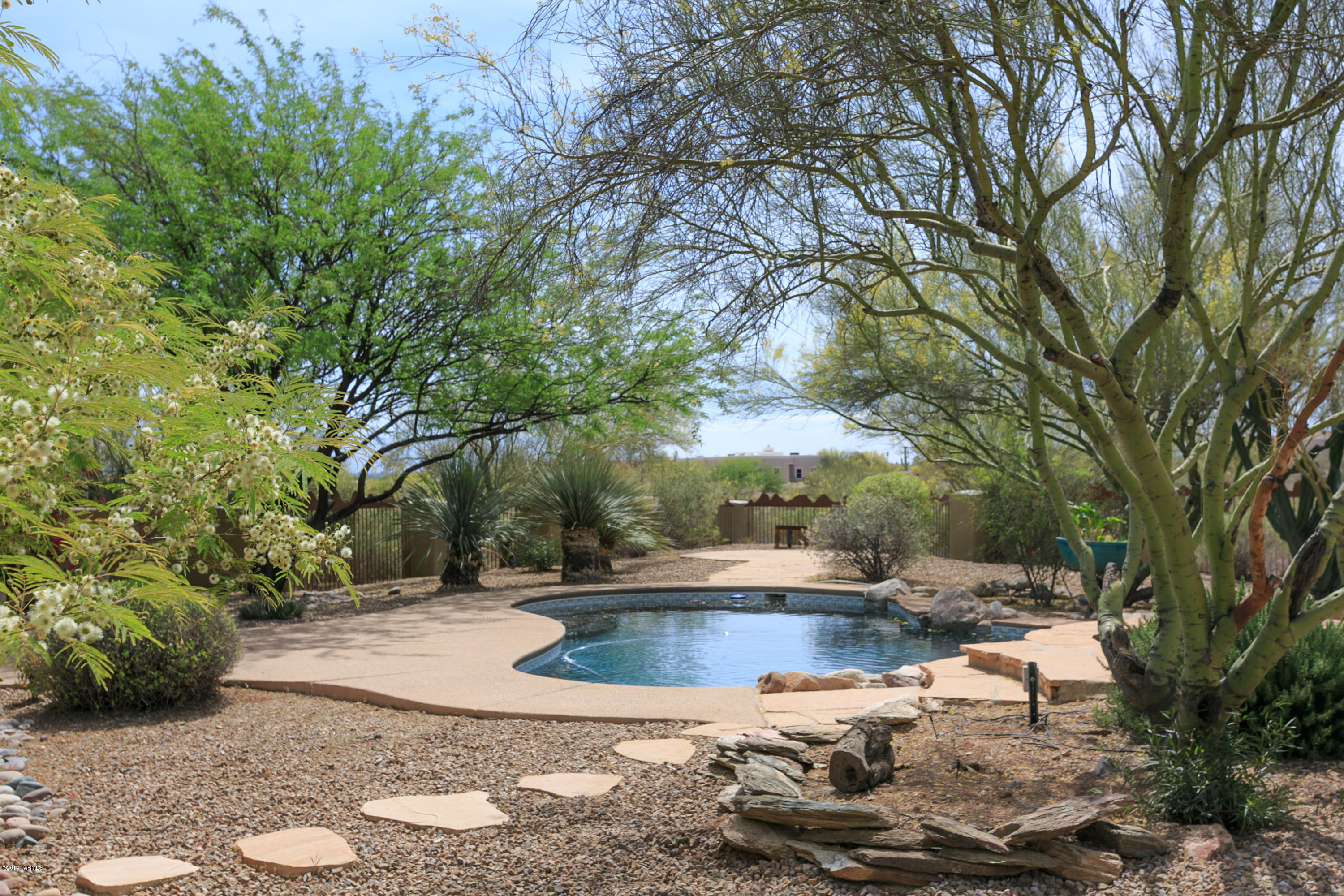 Outstanding custom built Santa Fe style home with 4 bedrooms/3 baths is on a gorgeous acre with stunning mountain views. Custom design and built by renowned architect Bob Fetterly using superior materials, peaky cedar plank ceiling with giant hand hone vega beams, hand painted talavera tile work in the baths and arched hall, refinished saltillo tile, niches and saguaro rib cupboard doors. Large gracious rooms, master and living room host charming bee hive fire places. Outdoor living at peace with nature, mature trees and low care low water landscaping surround the pool area, a rock waterfall connect the upper spa to the pool. Expansive riparian area behind the home allows for stunning city and mountain views. Court yard and sweeping exposed aggregate drive create great street appeal.