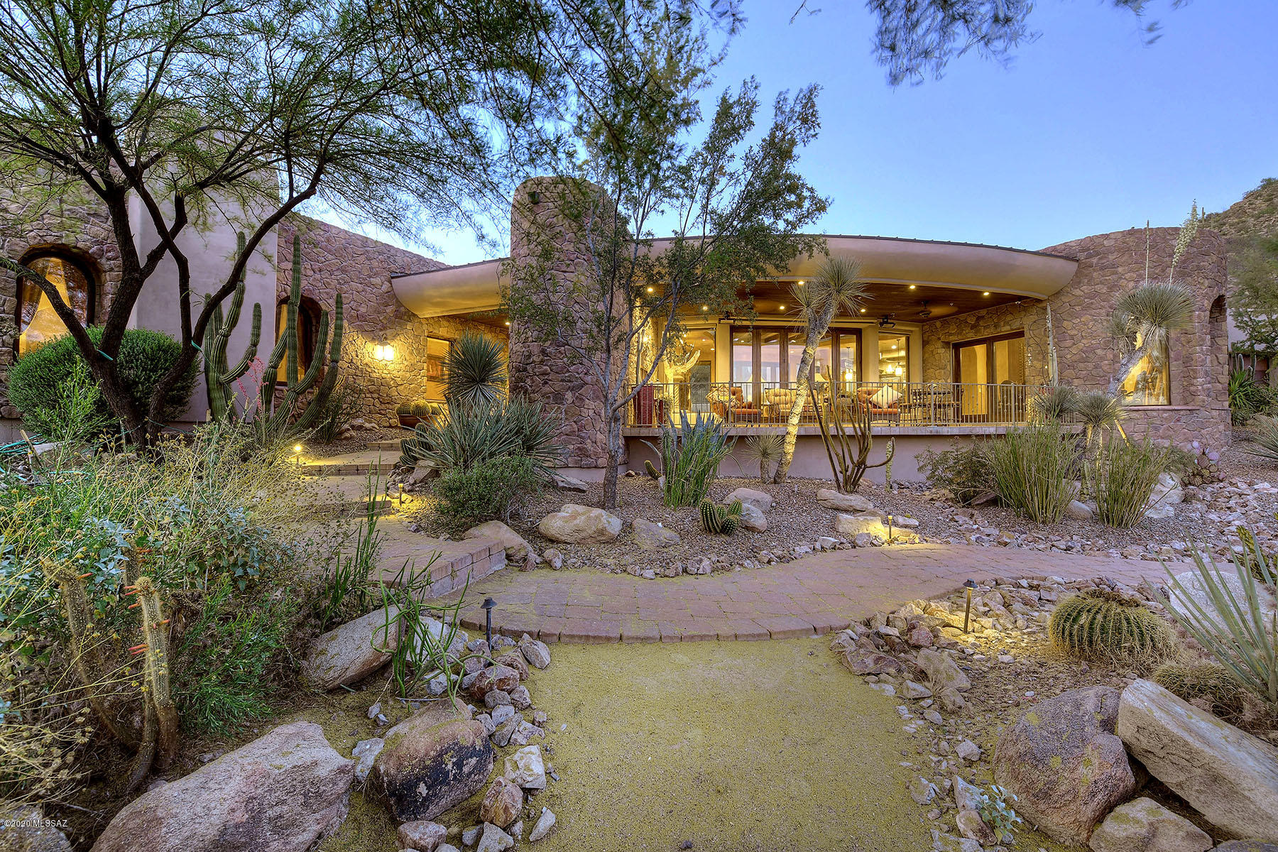 This dramatic, Ron Robinette designed, Southwestern contemporary is nestled at the end of a cul-de-sac on a private 4.75 acre lot in prestigious, gated Saguaro Ranch and offers panoramic mountain and valley views. Access the secluded subdivision by a tunnel through the mountain. The spectacular property includes a 4,594 sq. ft. main house and a 1,162 sq. ft. guest house complete with a living room & kitchenette. Highlights include a long & winding paver driveway, rugged stone walls, a grand entry & foyer, Venetian plaster walls, soaring beamed ceilings, 4 fireplaces, stone flooring, state-of-the-art media room, a library, a  pool/spa, outdoor kitchen an living room, and so many other custom features.front porch w/ ireplace and panoramic views and leads to rear yard with pool, spa, ramada