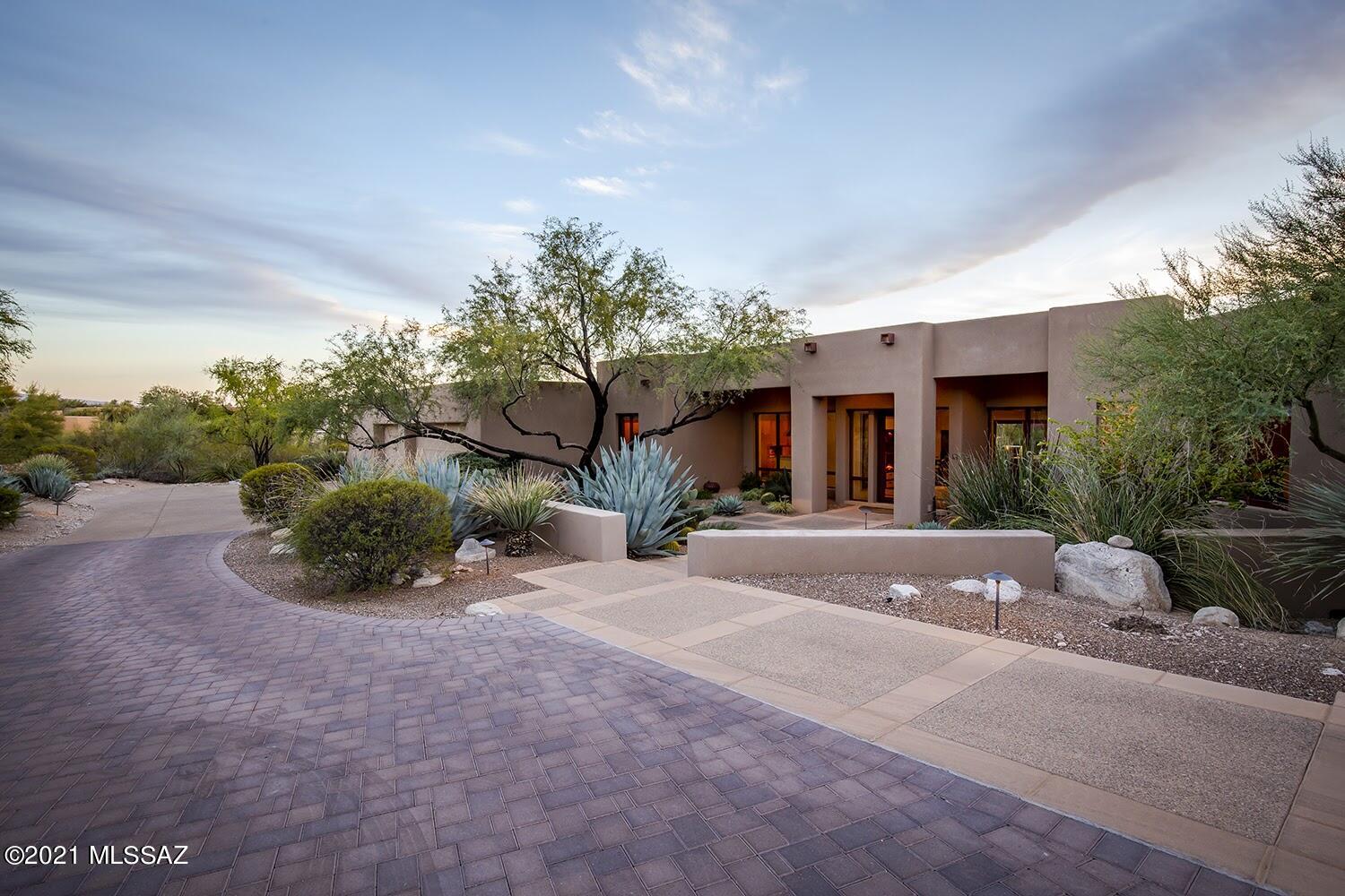 Stunning contemporary home sits on an elevated 1.57 acre lot in prestigious Cat.10. Custom built in 2002 of masonry stucco. Paver drive leads you to an enclosed front courtyard. Through the glass entry door you'll be amazed by the beautiful sandstone floors thruout, great room with stack stone fireplace & wall of sliders to the resort-like backyard with outdoor kitchen, infinity edge pool/spa, firepit, putting green, solar shades, misters, & amazing views of the city & beyond. The kitchen is made for entertaining with top-of-line appliances & 2 dishwashers. The primary bath has a workout area & separate his & her sides joined by tiled walk-in shower. 1 of the 4 bedrooms is used as an office with built-ins; the other 2 are full en-suites. 3-car garage has a bonus cooled workshop. Must see!