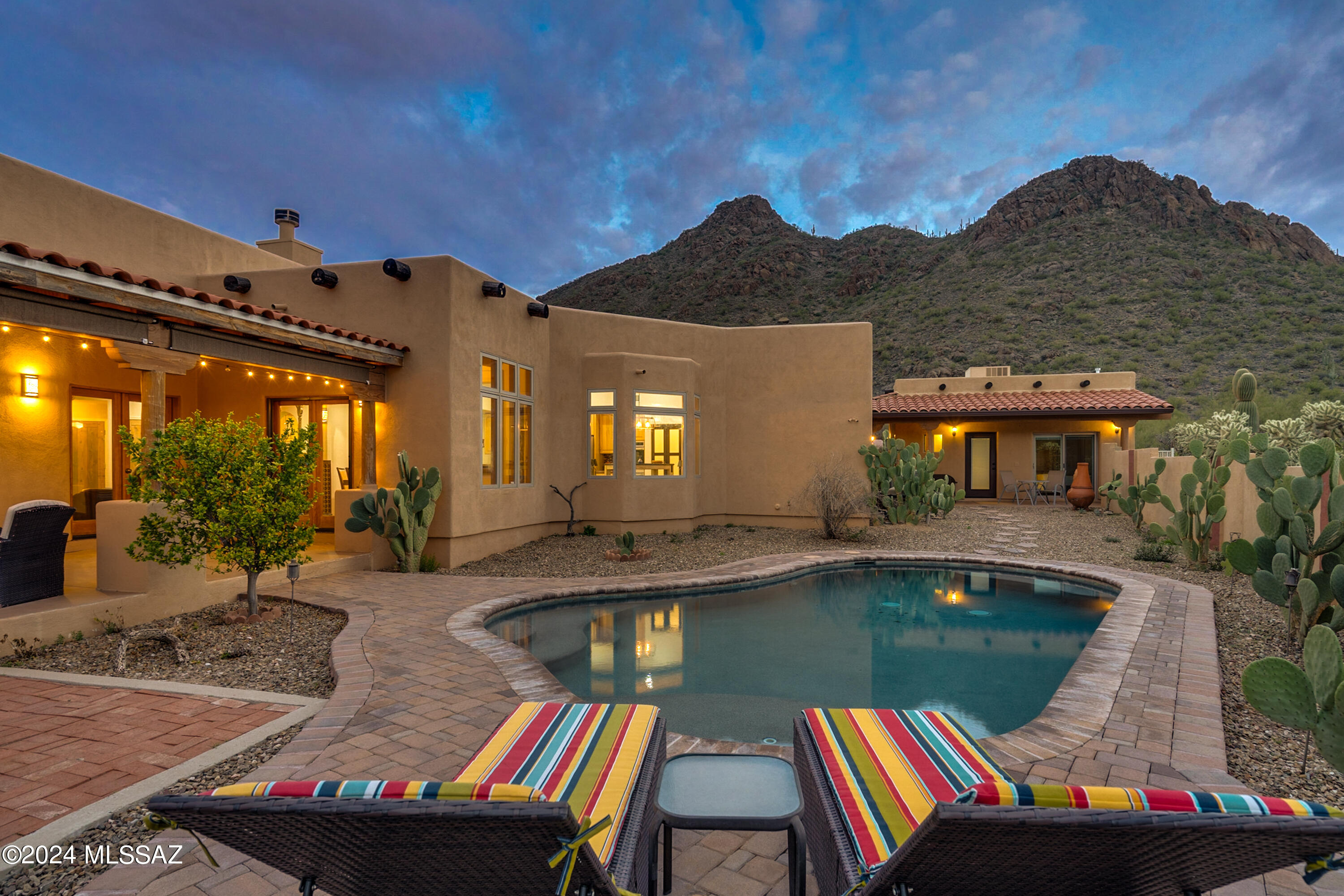 Looking for luxury and comfortable living? Look no further. This move-in ready custom home has it all. A Santa Fe-style home located in a cul-de-sac in an intimate community, surrounded by views of Tucson Mountain Park and breathtaking sunrises and sunsets. From the moment you enter this home, you will be captivated by the beautiful Southwest architectural design. The split floorplan home, nestled on 3.5 acres of private Sonoran Desert, features numerous upgrades. The main house includes an en-suite, two bedrooms, 2.5 bathrooms, living room with a fireplace, exposed wood beams and columns, and a dining room with French doors opening to a spacious walled-in backyard. The kitchen boasts two ovens, an electric cooktop, stainless steel appliances, a walk-in pantry, stained concrete countertops and breakfast bar. The back patio area and the pebble sheen pool are perfect for entertainment or quiet time. The guest house built in 2019 & offers 488 sqft with one bedroom, a seating and eating area, a full kitchen and bath, separate septic, and propane tank.